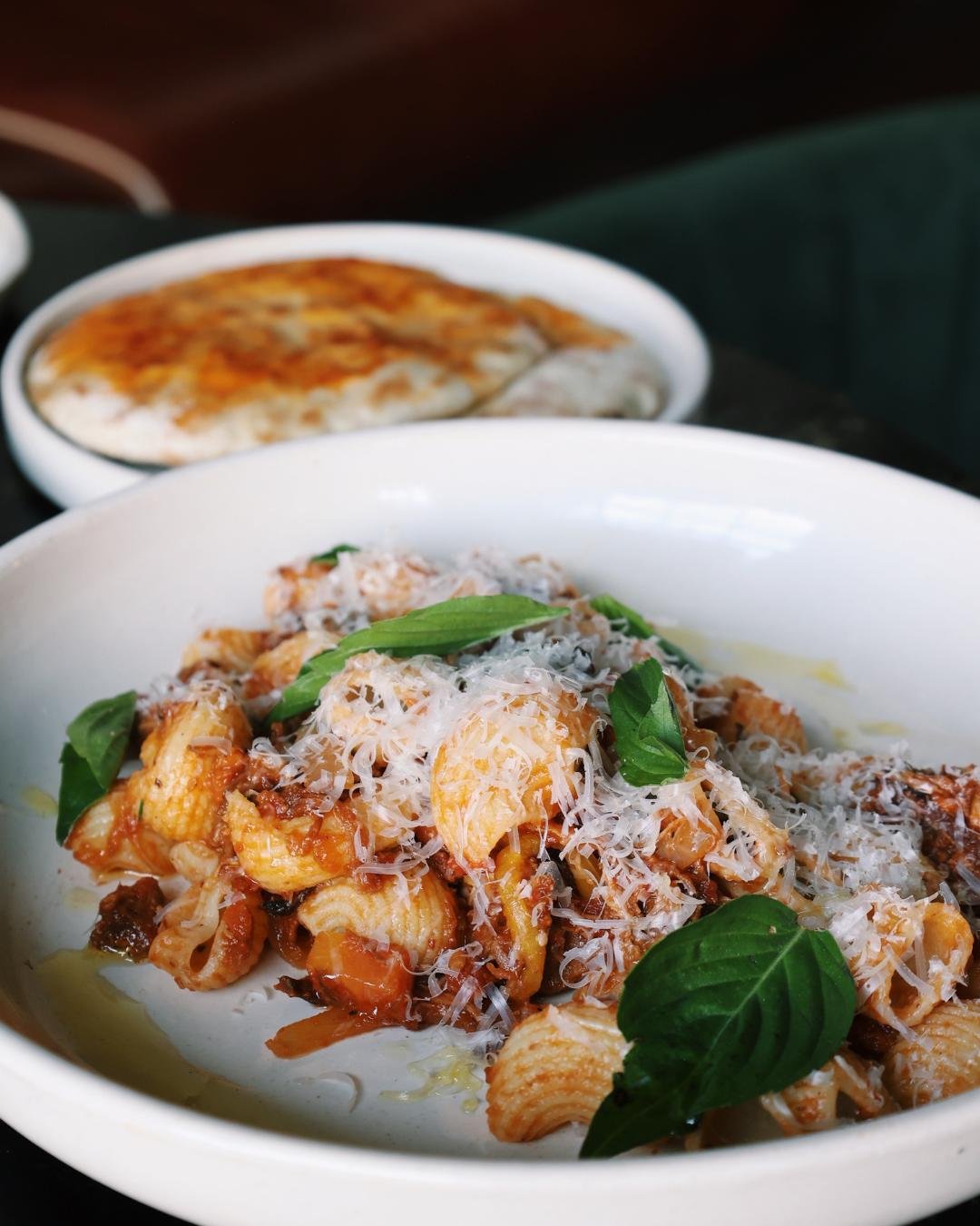 a plate of handmade pasta with fresh ground cheese and basil on top 