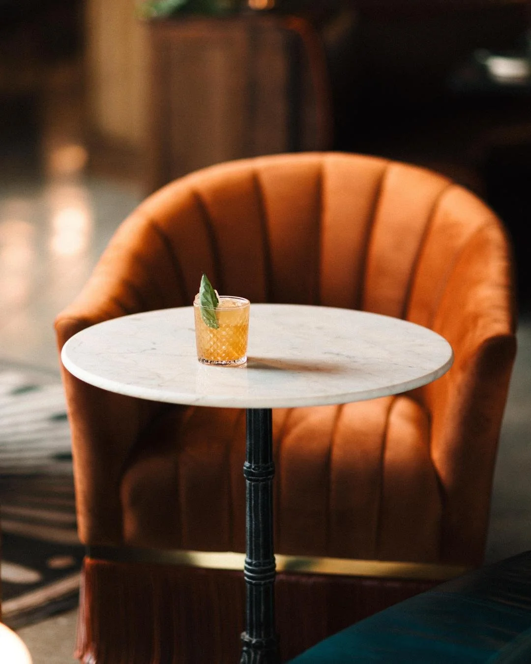 A cocktail table and leather chair at the Red Herring Cocktail lounge a hand crafted cocktail sits on the table