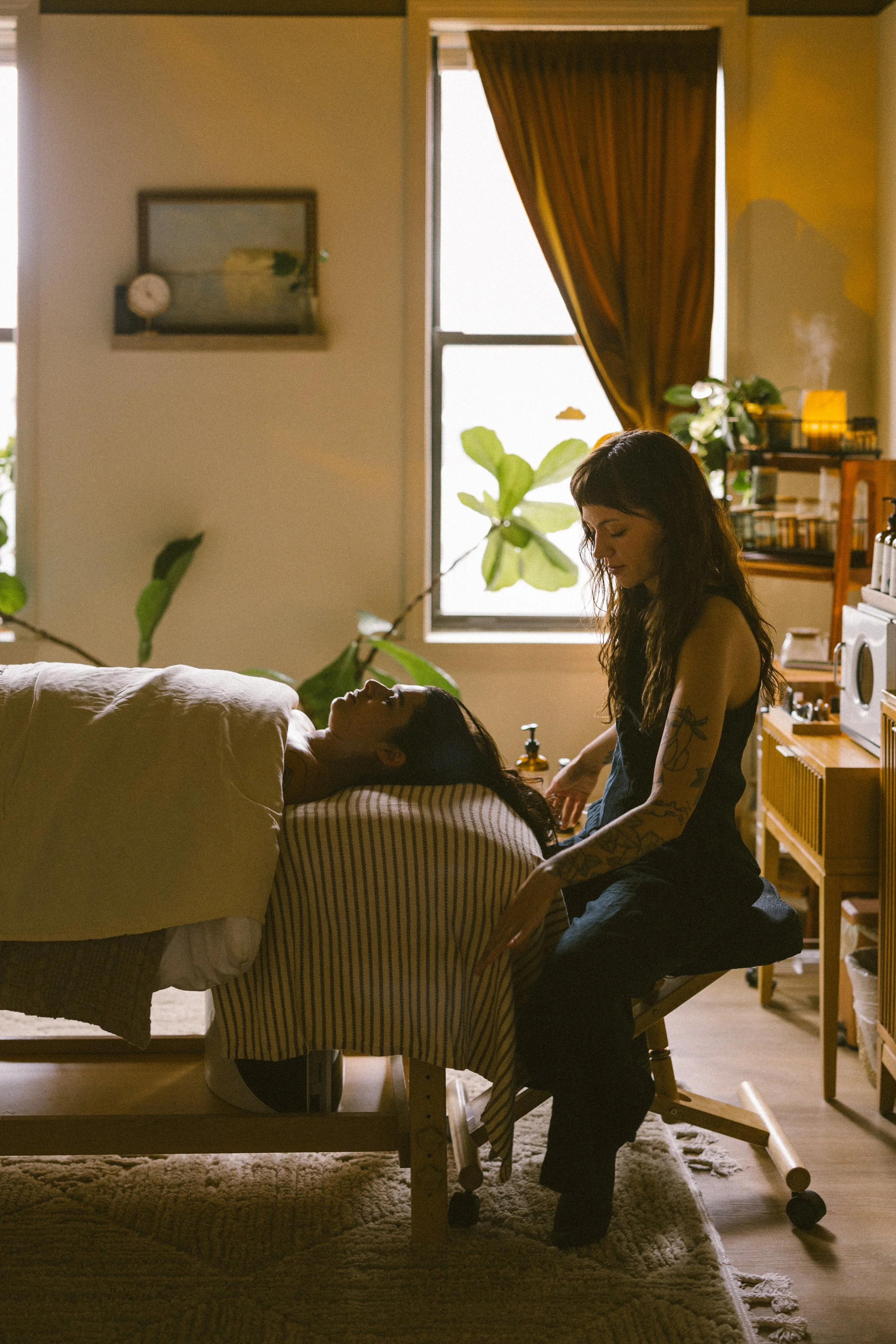 Esthetician preparing to perform a massage-forward facial treatment on a relaxed client in a calming treatment room in Biddeford, Maine.