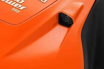 Close-up of an orange Husqvarna Automower with a small black sensor mounted on the body.