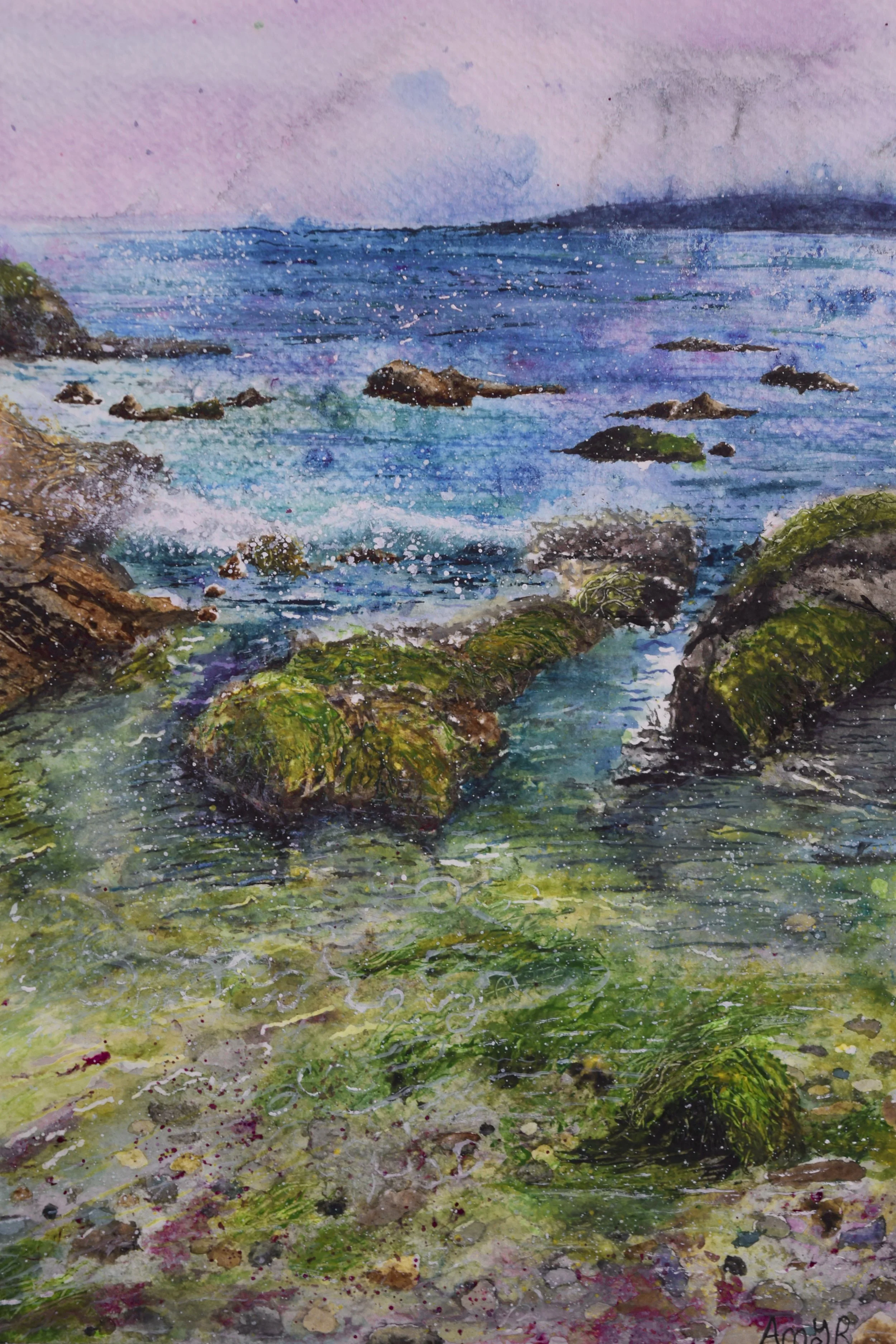 Watercolor painting of a rocky seaside scene with moss-covered rocks, blue ocean waves, and a purple sky.