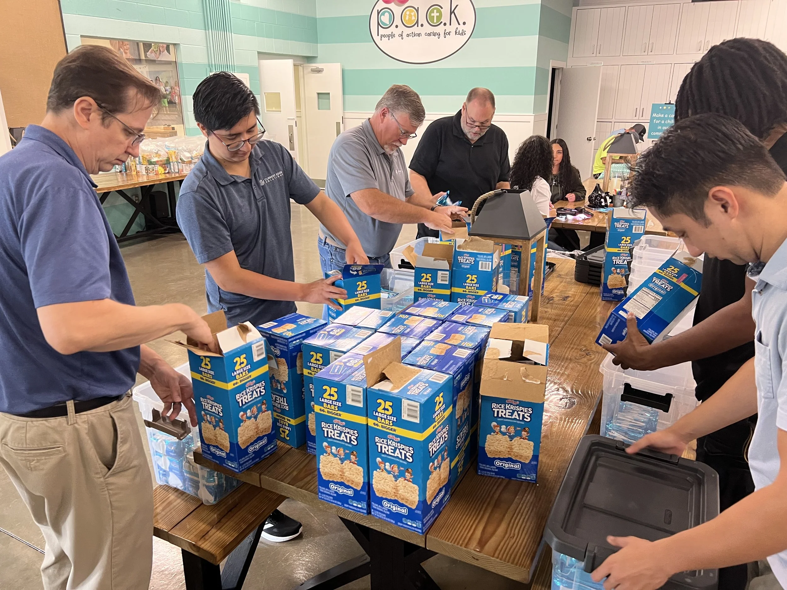 People packing boxes of Rice Krispies Treats at a community event table.