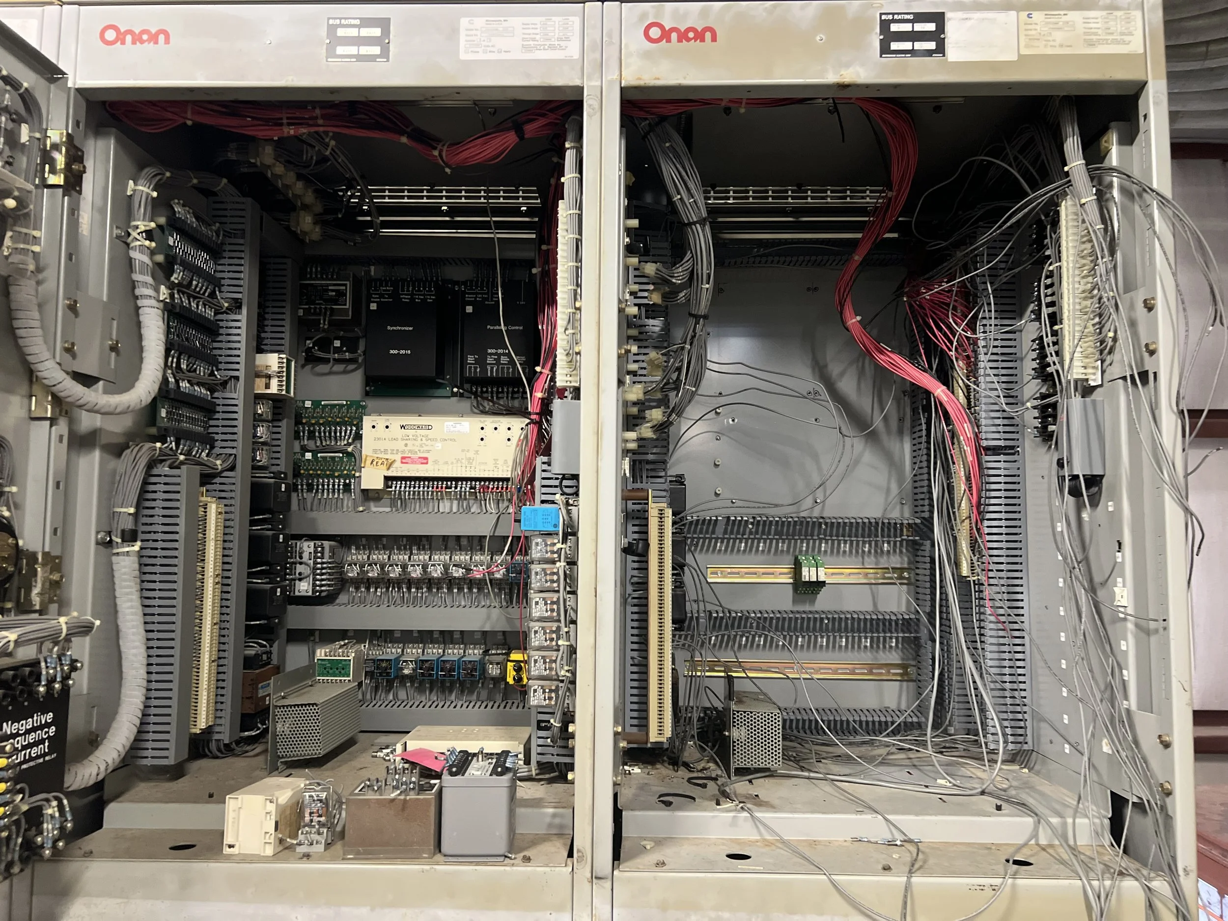 An open electrical control panel with wires, circuit boards, and electronic components inside.