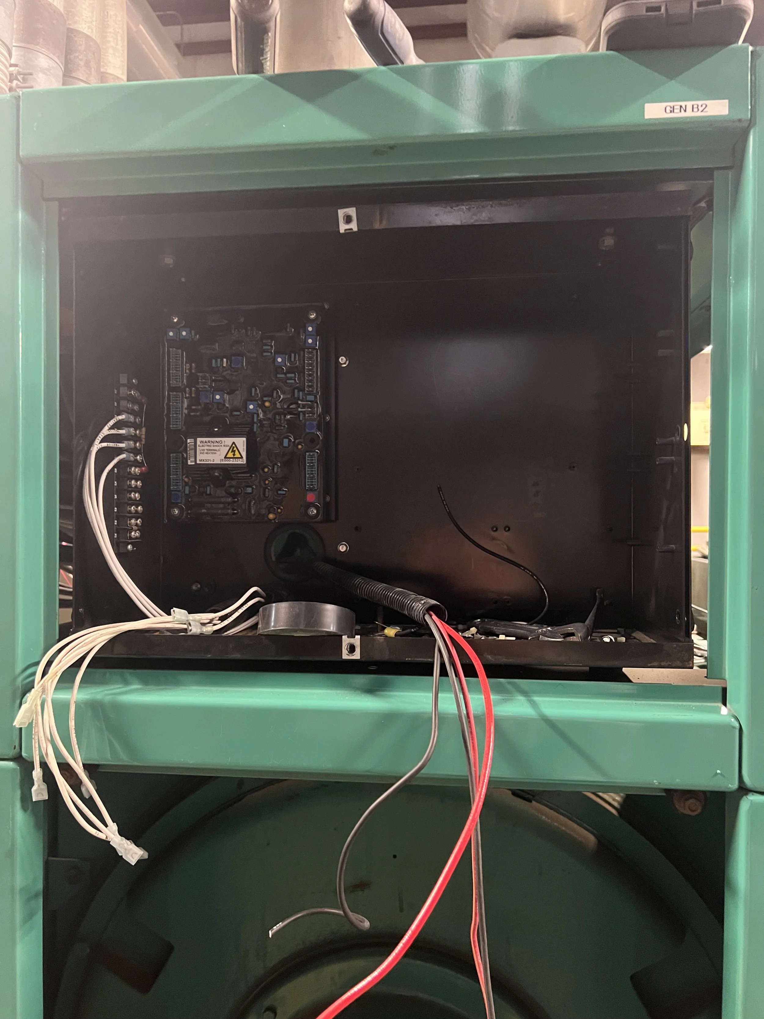 Empty green machine with exposed internal circuit board and wires inside.
