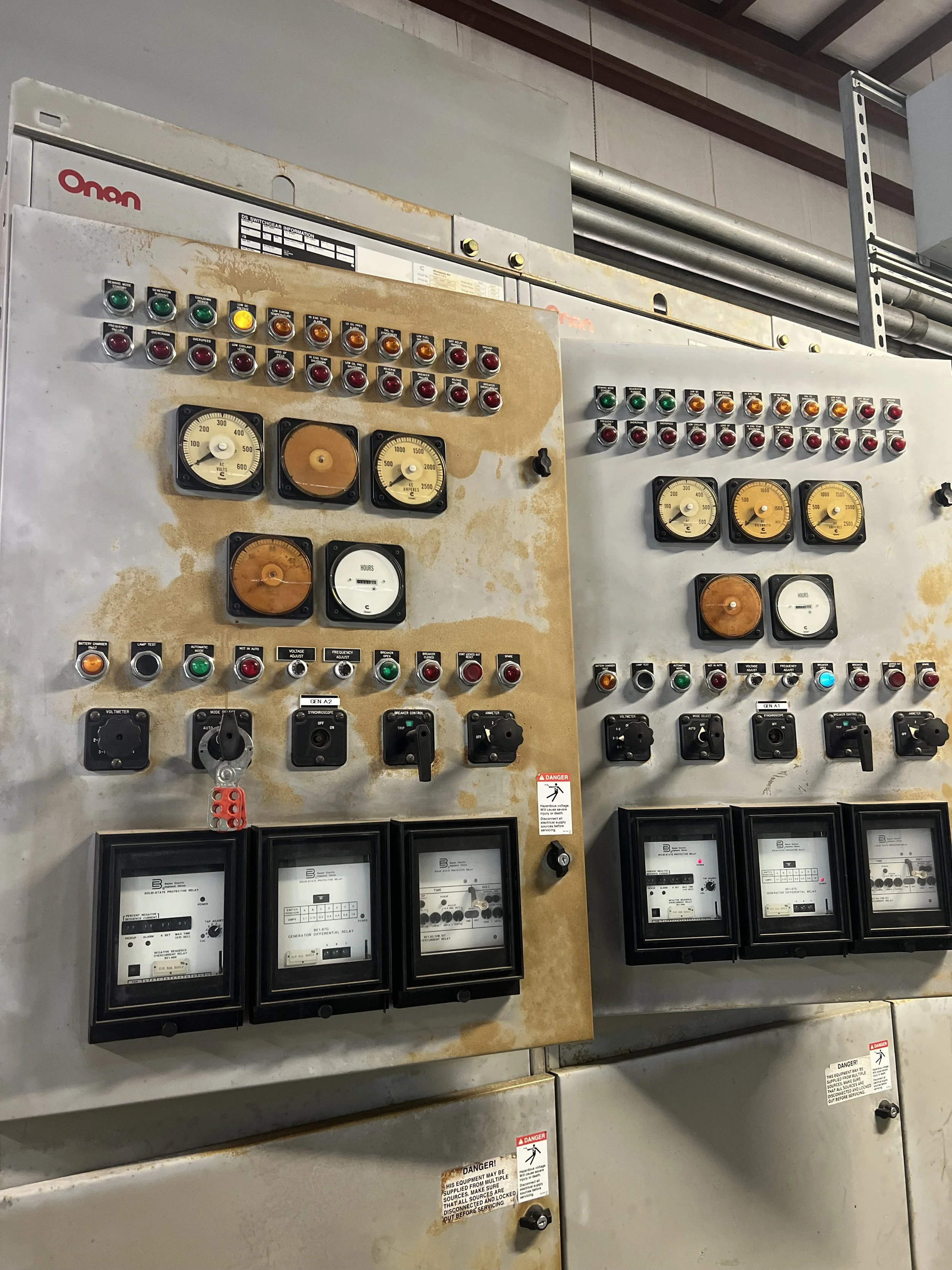 An industrial electrical control panel with numerous indicator lights, meters, switches, and meters, showing signs of rust and wear.