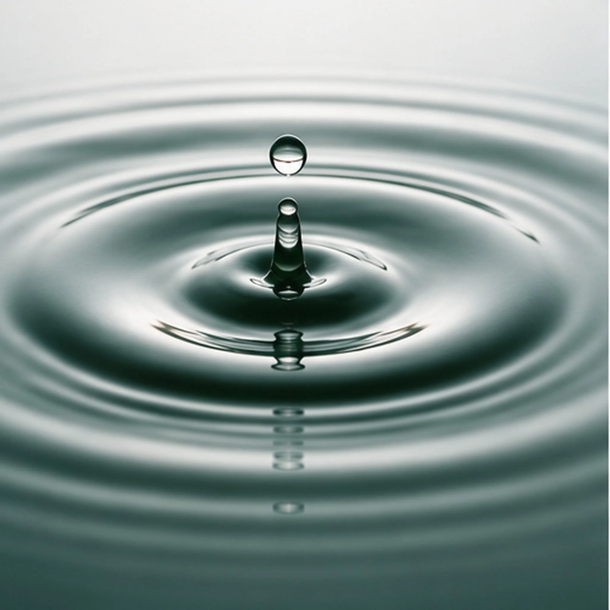 Close-up of a water droplet hitting the surface, creating ripples.