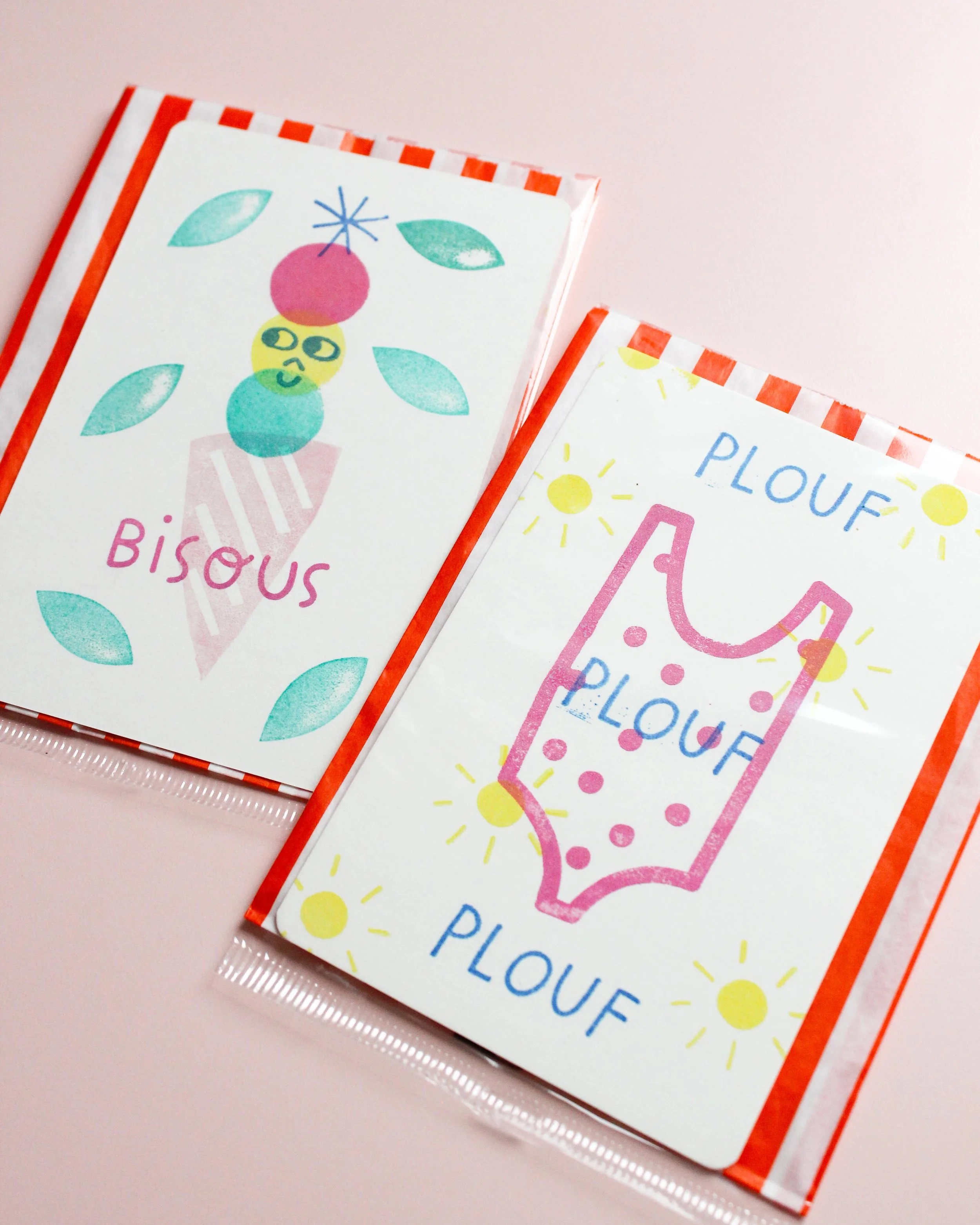 Deux paquets de bonbons, chacun avec une illustration colorée et des mots en français, posés sur une surface rose pâle.