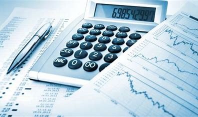 Calculator, pens, and financial charts on a desk, related to accounting or finance.