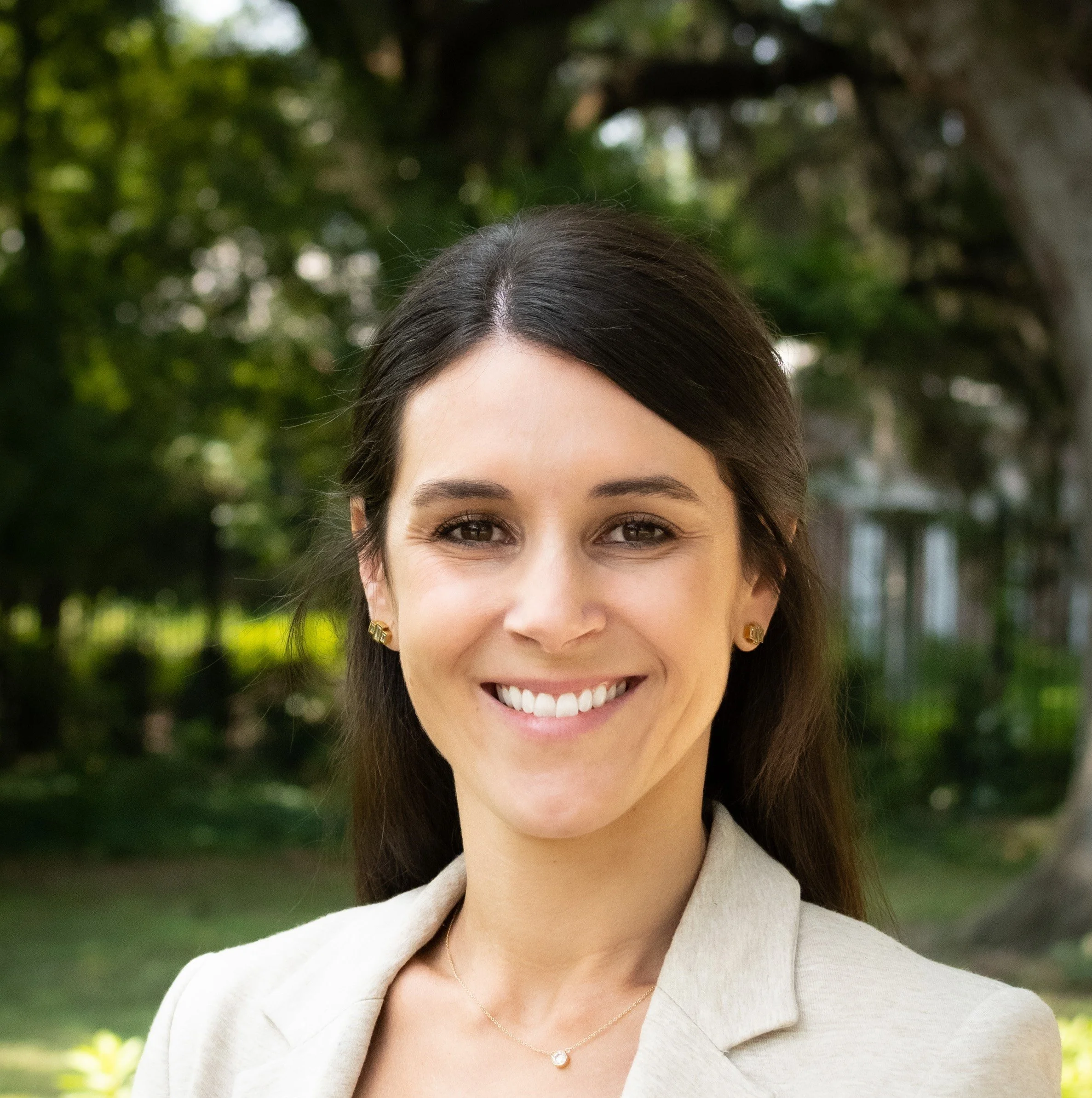Smiling person outdoors with green foliage background
