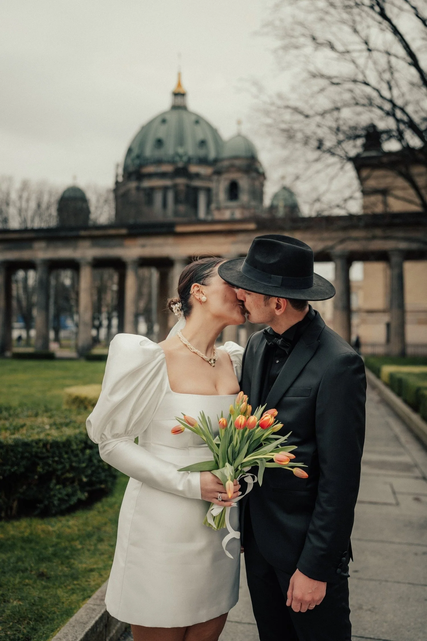Couple kissing in the Lustgarten with the Berlin Cathedral behind them
