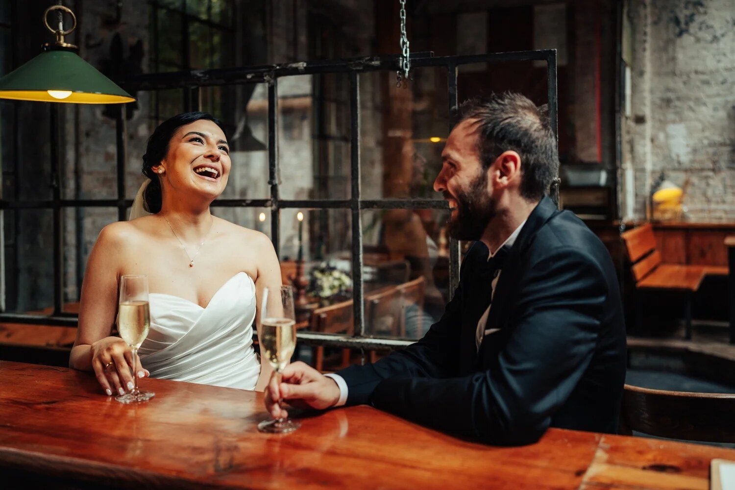 Bride and groom raising a glass at a café table after their wedding in Berlin