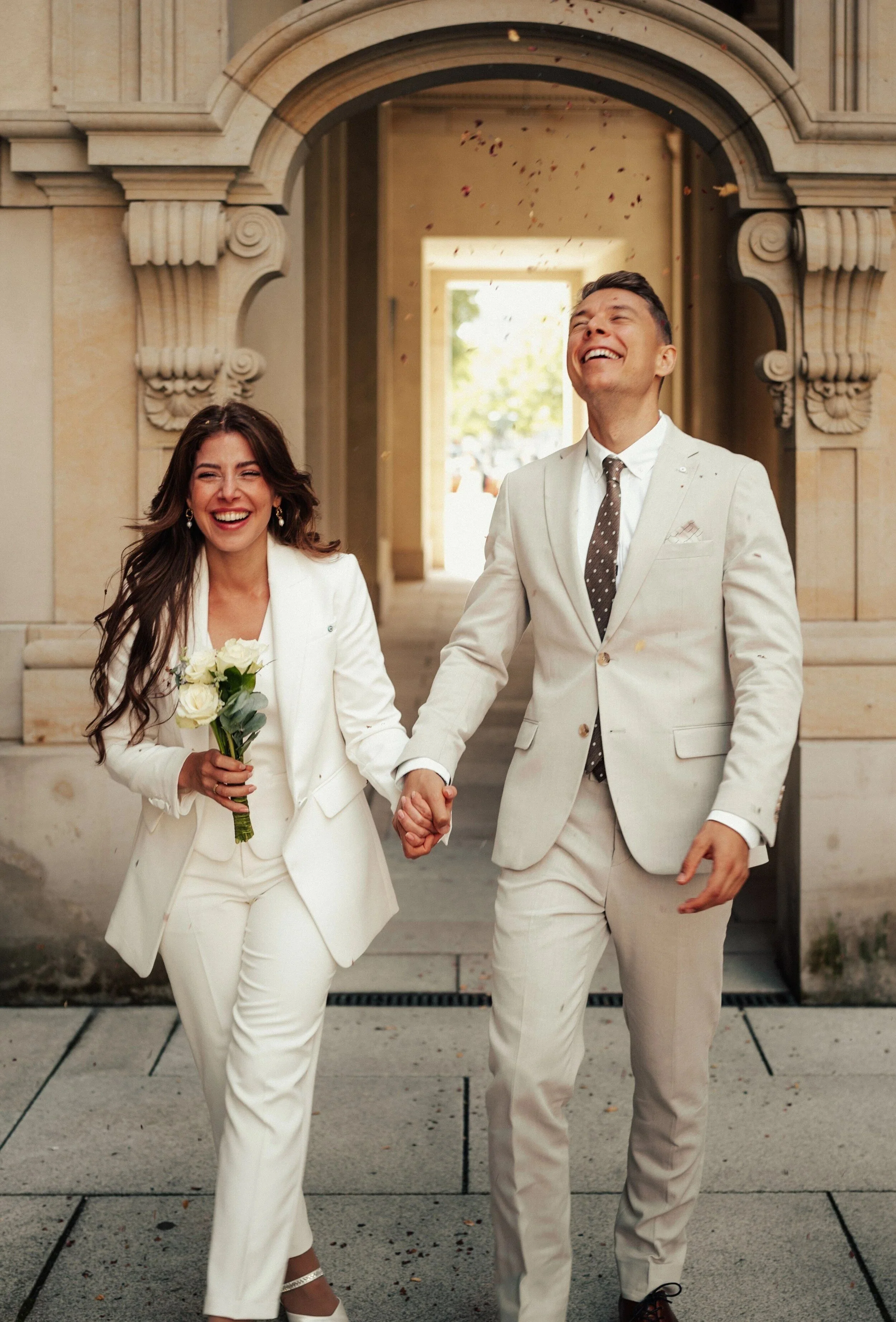 Couple walking hand in hand out of a sandstone archway after their civil wedding in Berlin