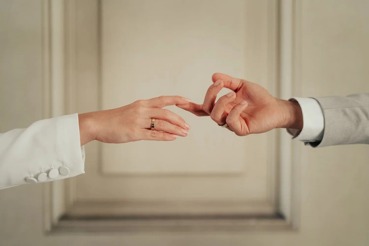 A couple's hands reaching for each other in front of a panelled door