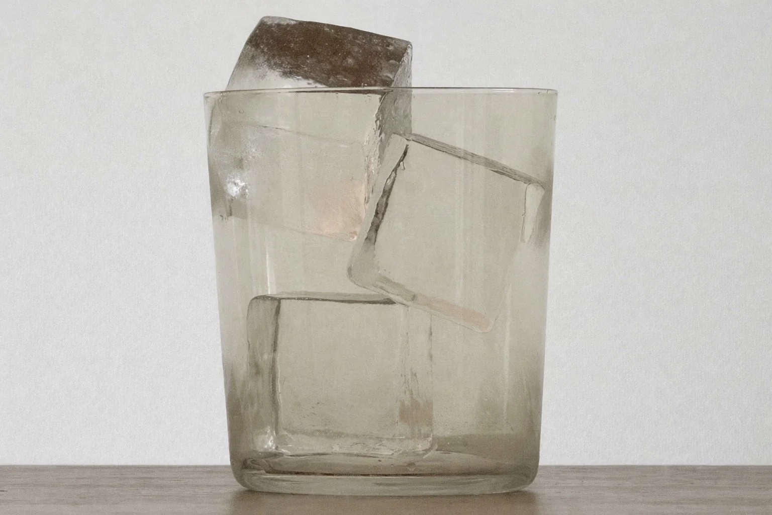 A clear glass filled with water and three large ice cubes.