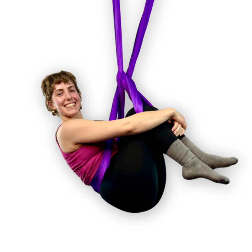 Intermediate aerial yoga student practicing flow sequence in hammock