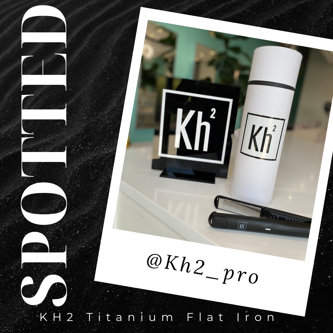 A display of KH2 titanium flat iron product, including a white cylindrical container, a black logo sign, and a black flat iron tool on a white surface with a black background.