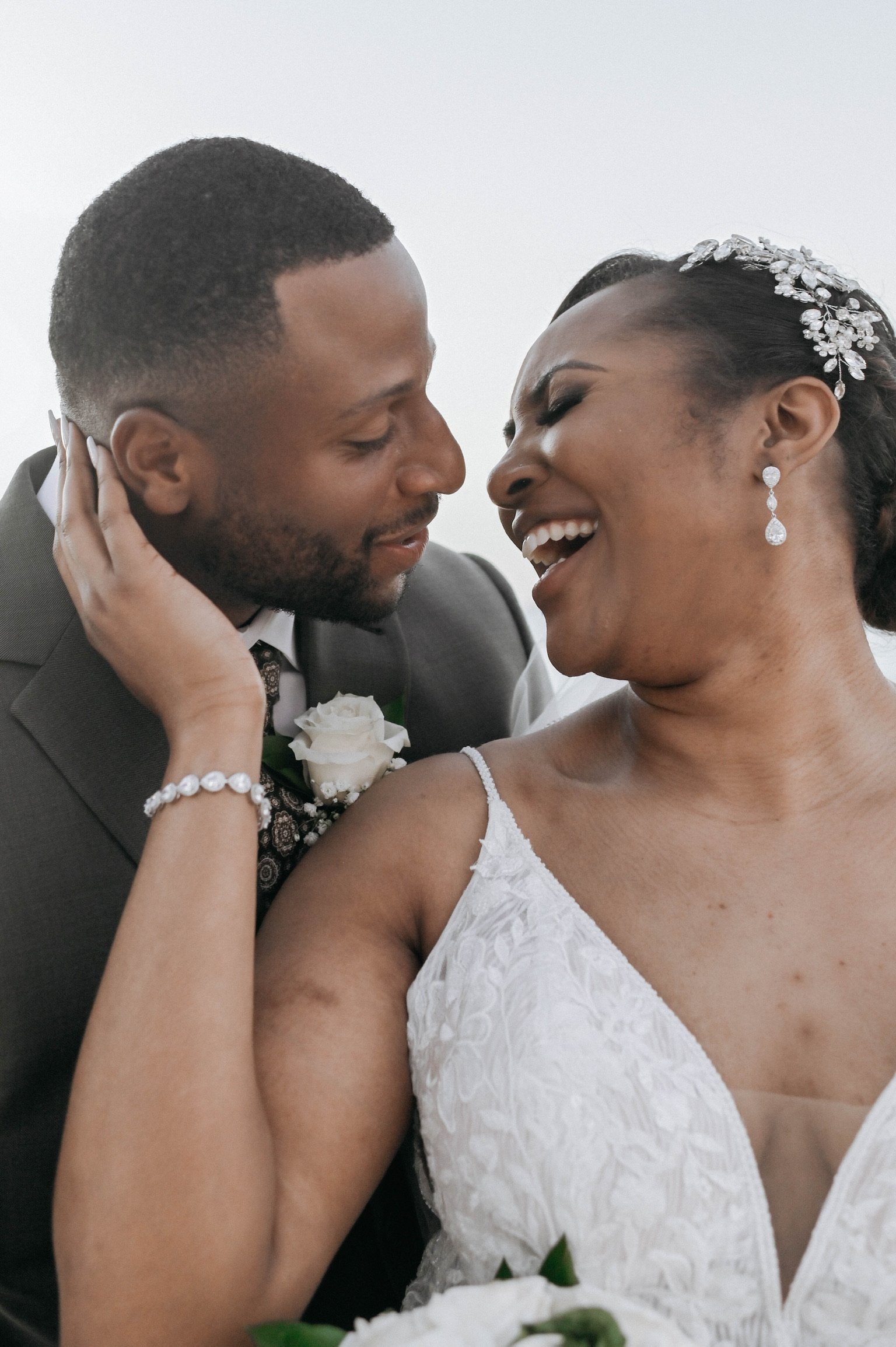 A bride and groom sharing a joyful moment on their wedding day, close-up of their faces smiling and laughing