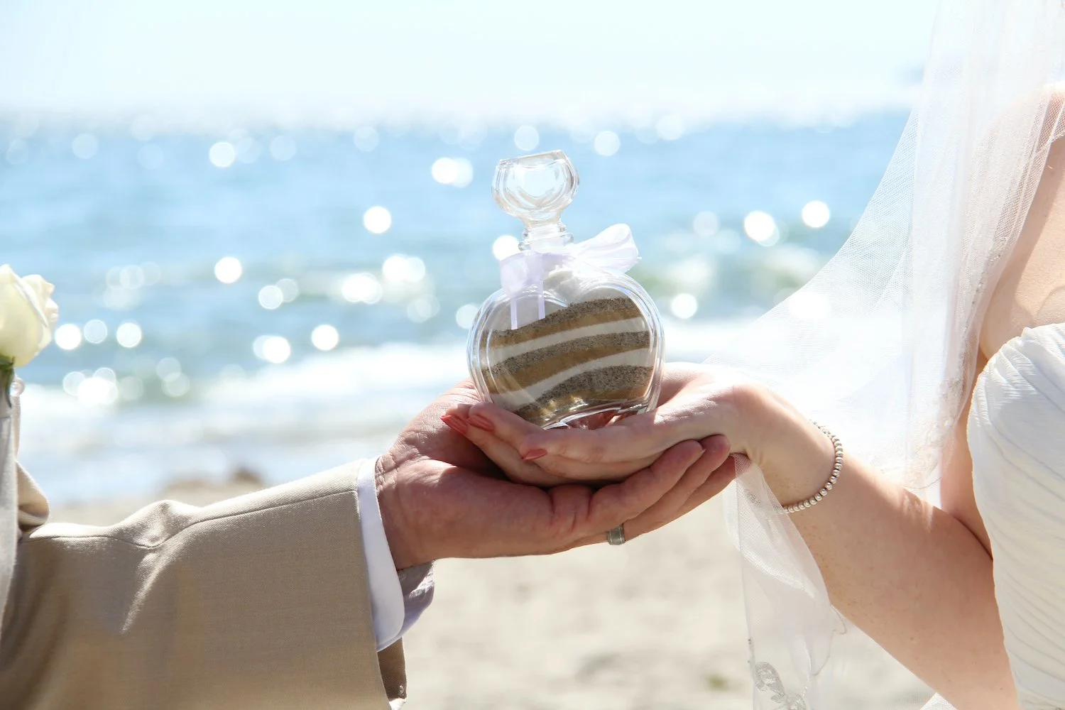 Bride and Groom holding sand at Santa Barbara vow renewal overlooking the ocean