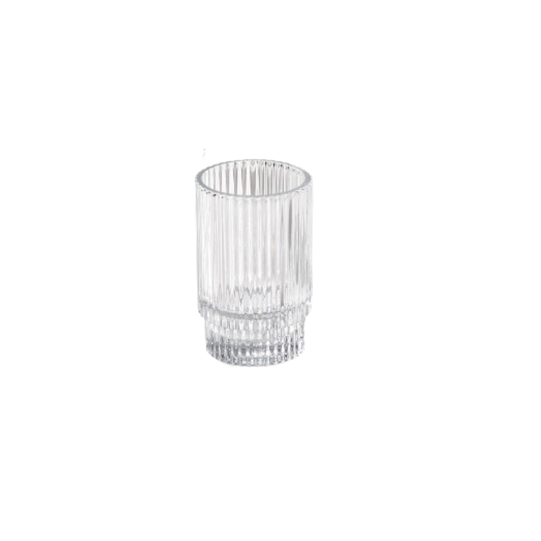A clear, ribbed glass tumbler with vertical lines, empty and standing on a plain white background.