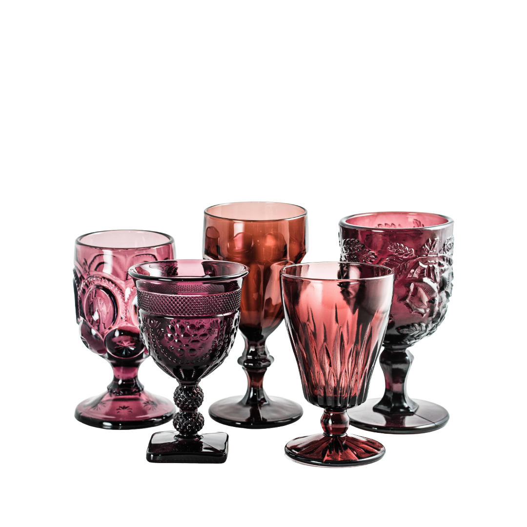 Six decorative pink and reddish glass goblets with various intricate patterns, arranged on a white background.