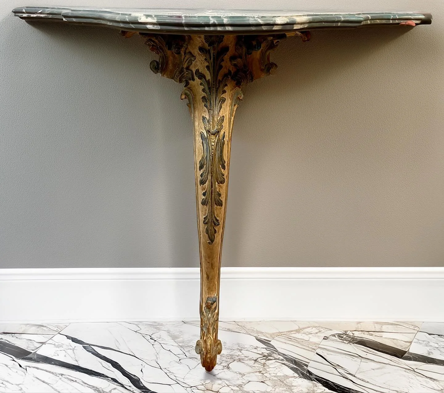 This elegant console features an ornate carved base with rich acanthus leaf detailing and a hand-painted aged finish that highlights its timeless craftsmanship. Topped with a beautifully veined faux marble top, it embodies classic Italian design and 