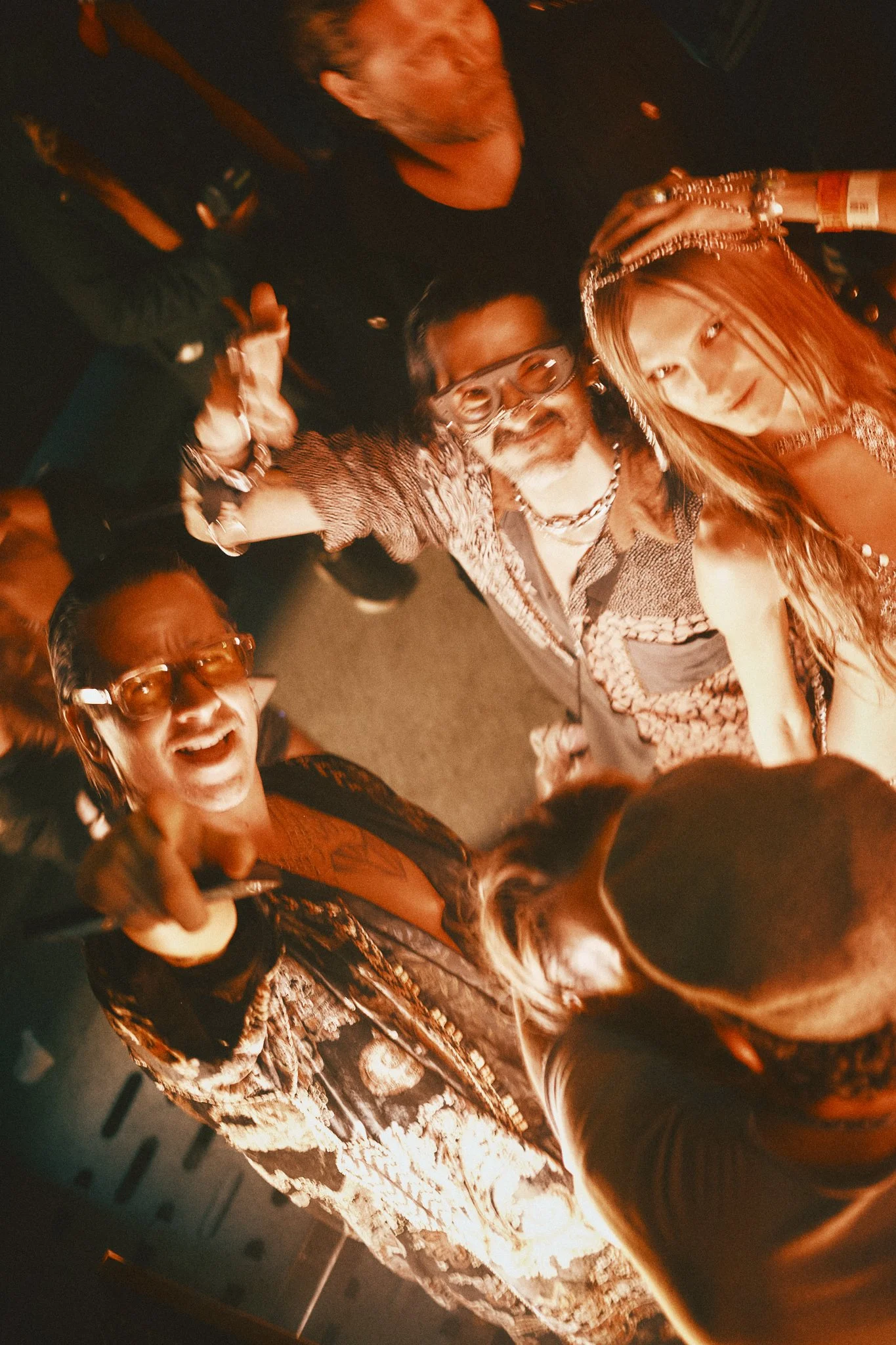 Group of people at a party taking a selfie with a wide-angle camera, looking up at the camera and smiling.