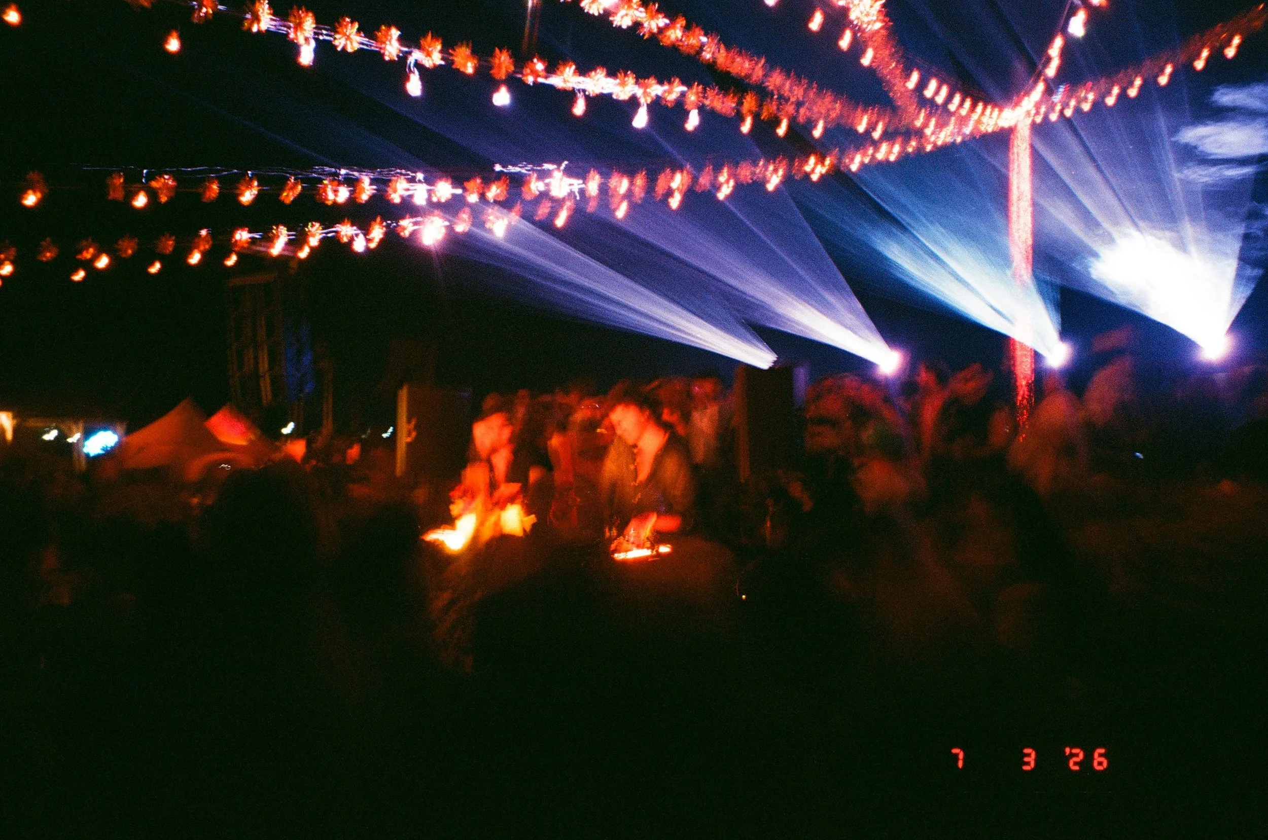 Night scene of DJ booth and string lights in the sky, with silhouettes of people gathered below, at Amarás Oaxaca Experience 2026.