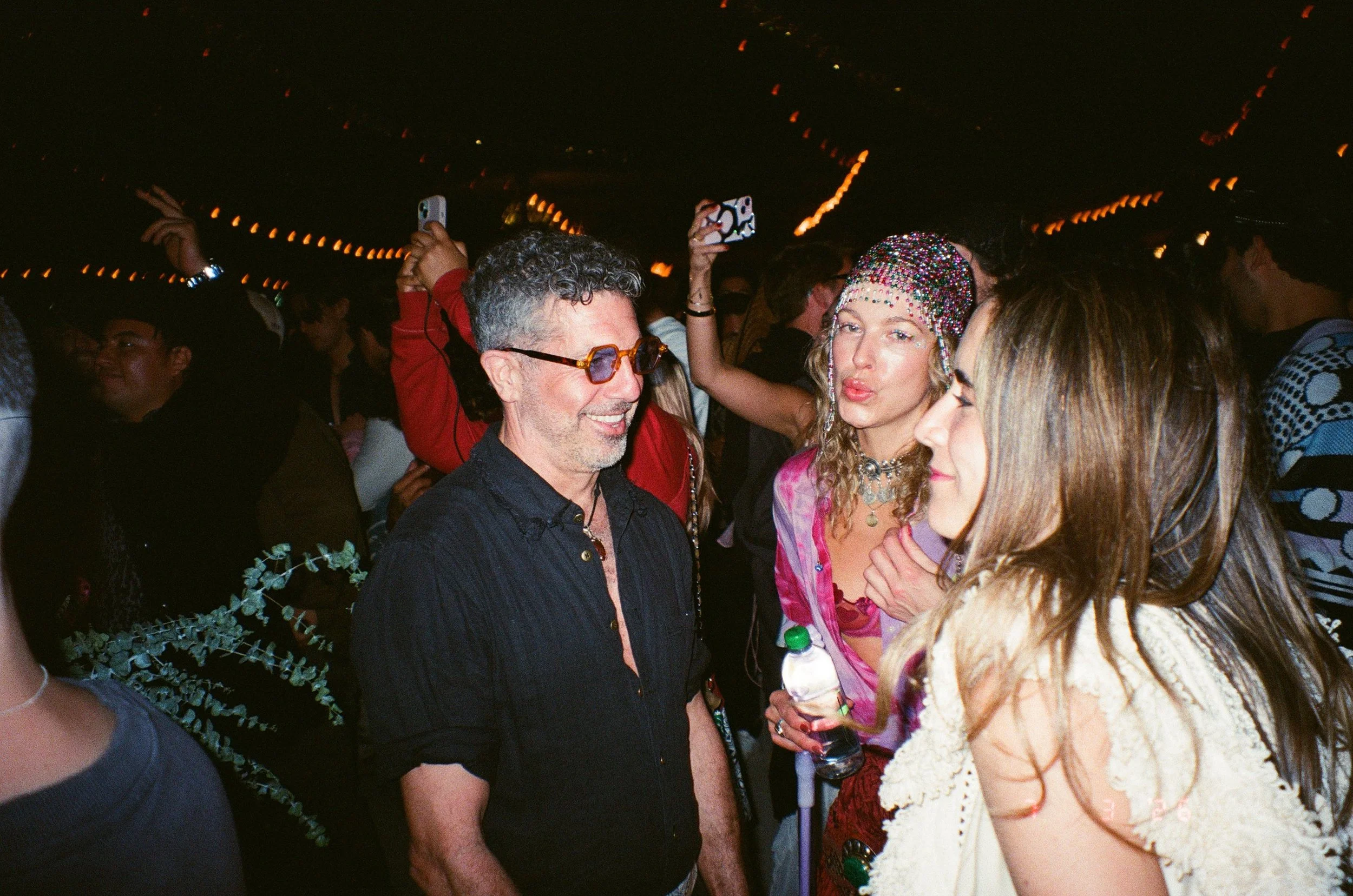 People dancing and socializing at Amarás Oaxaca Experience 2026 with string lights overhead in a dark setting.