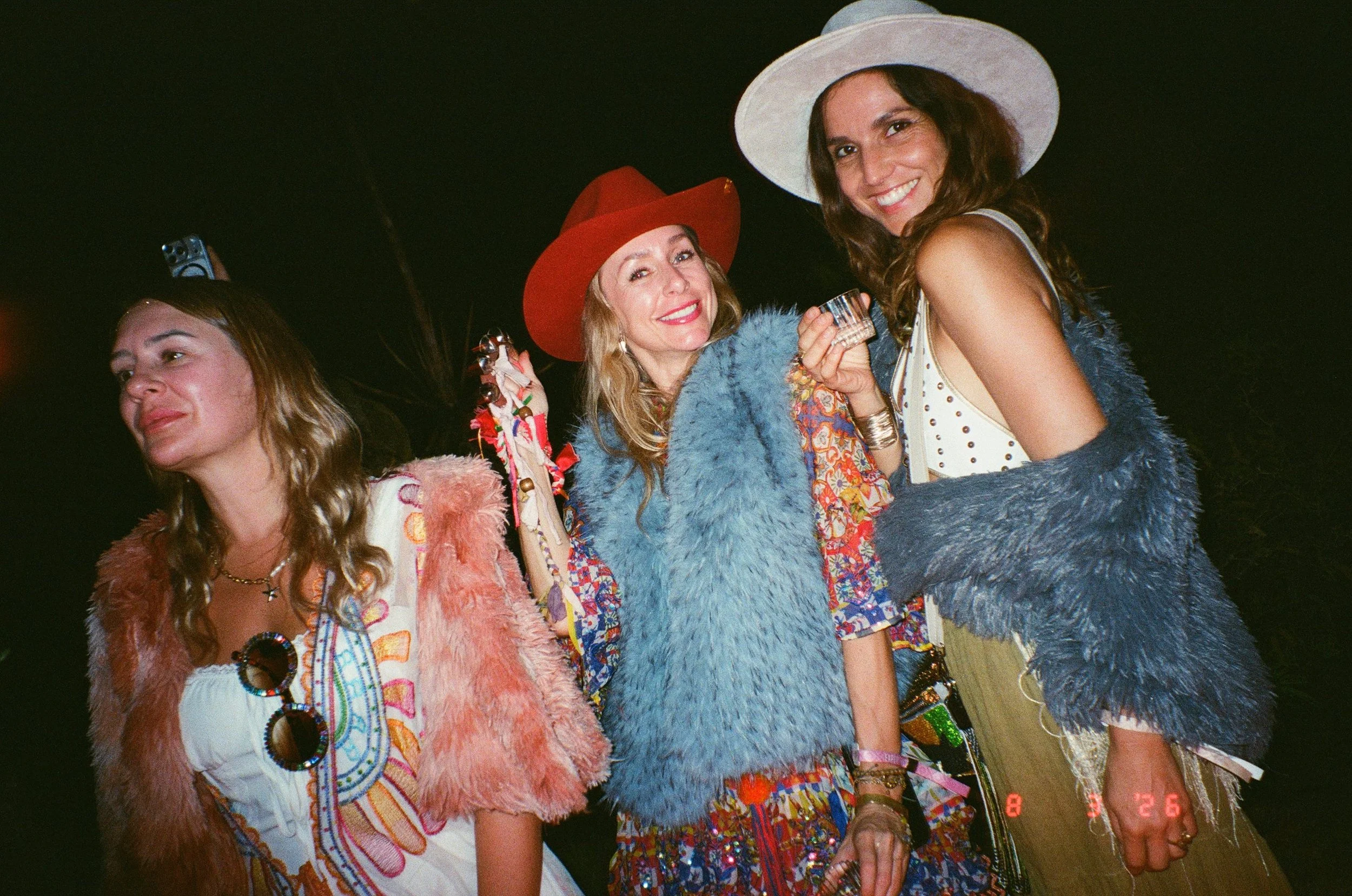 Three women dressed in colorful, retro-style clothing and fur vests, smiling at Amarás Oaxaca Experience 2026.
