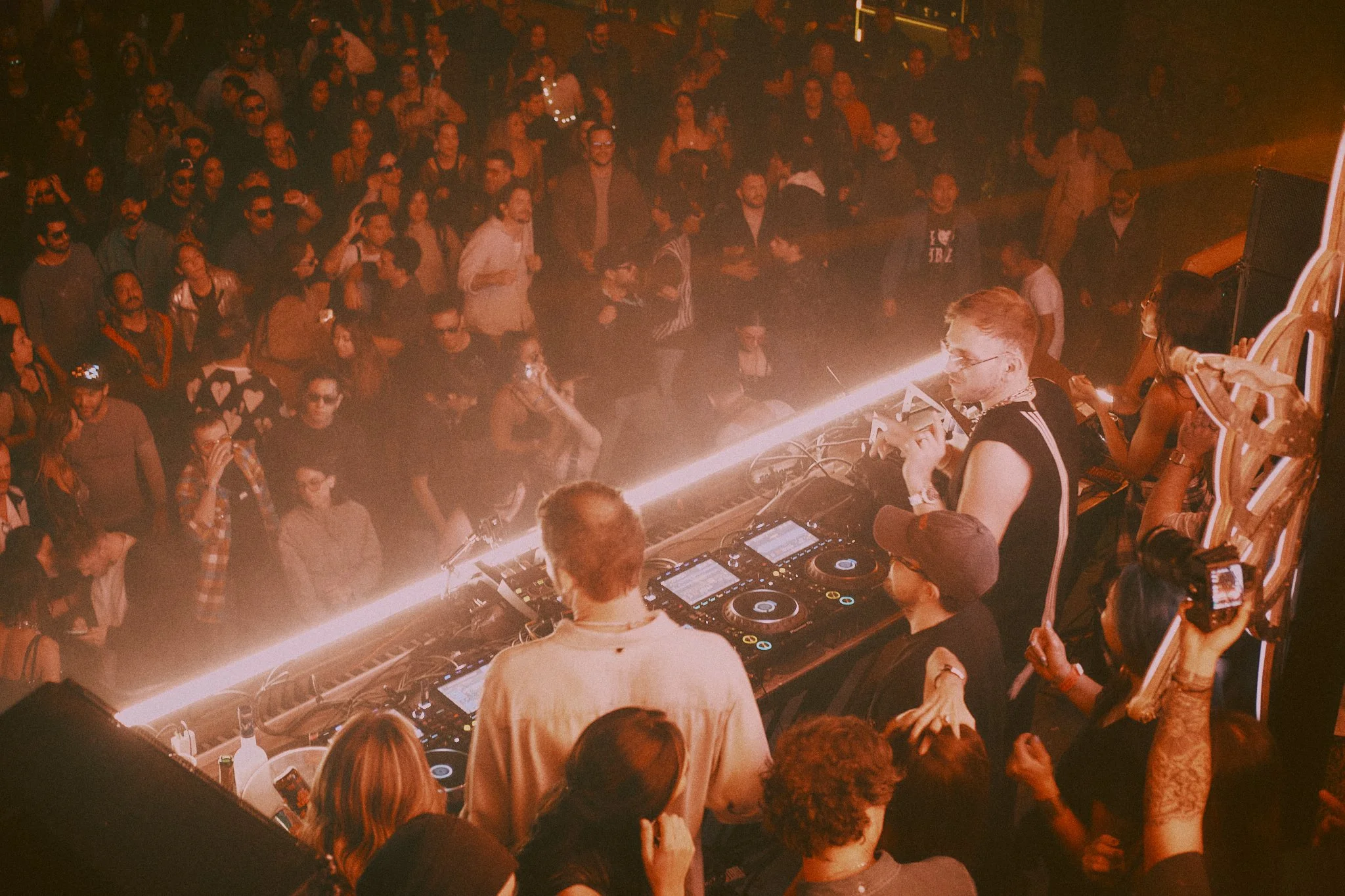 Crowd of people dancing and socializing at Mayan Warrior Art Car during Mexico City Art Week 2026 with Monolink and Colyn performing on stage behind a LED-lit railing.