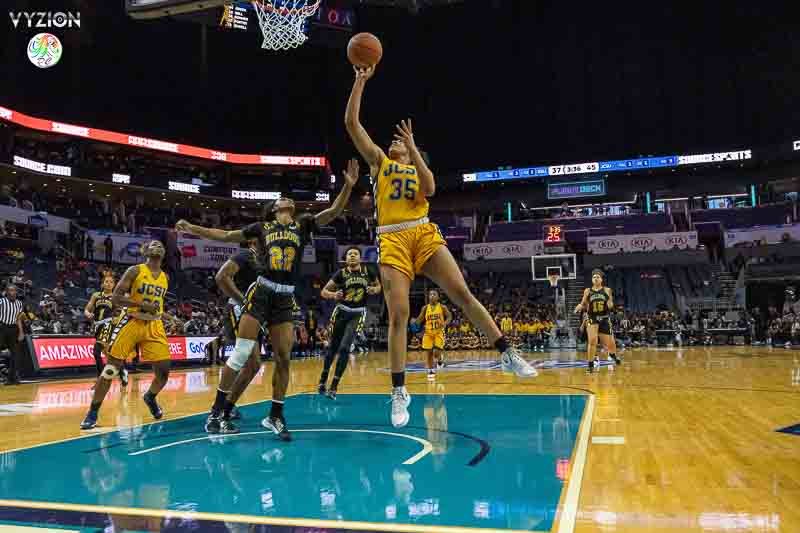 Women basketball game where player in yellow jersey number 35 jumps to shoot and player in black jersey number 15 defends.
