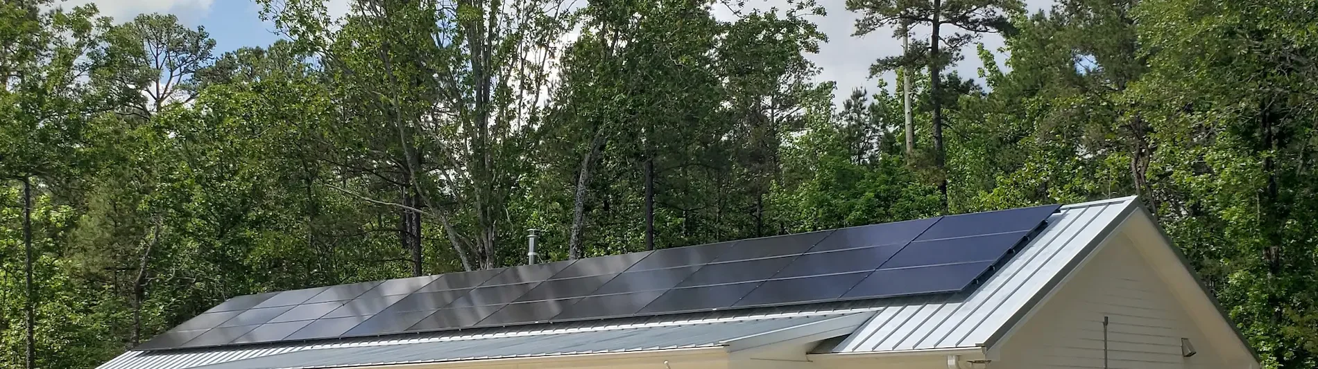 House with solar panels on the roof surrounded by trees.