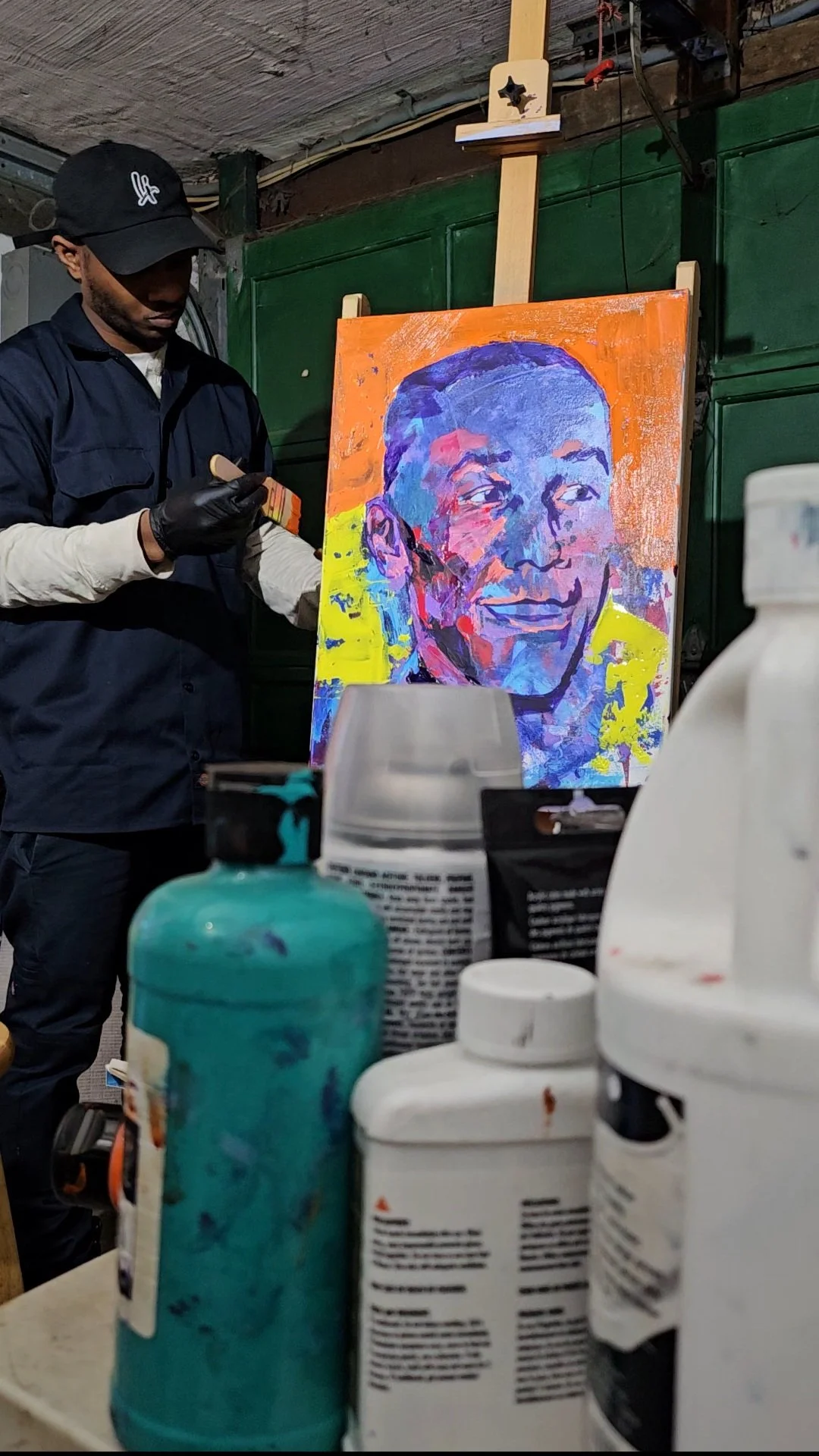 ​Artist at Littles Art studio working on a custom expressionist portrait commission using vibrant blue, purple, and yellow acrylic paints.