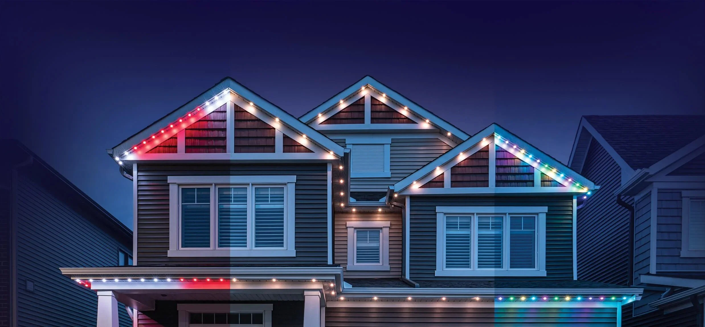 A house decorated with multicolored Christmas lights on the roof and eaves, set against a dark evening sky.