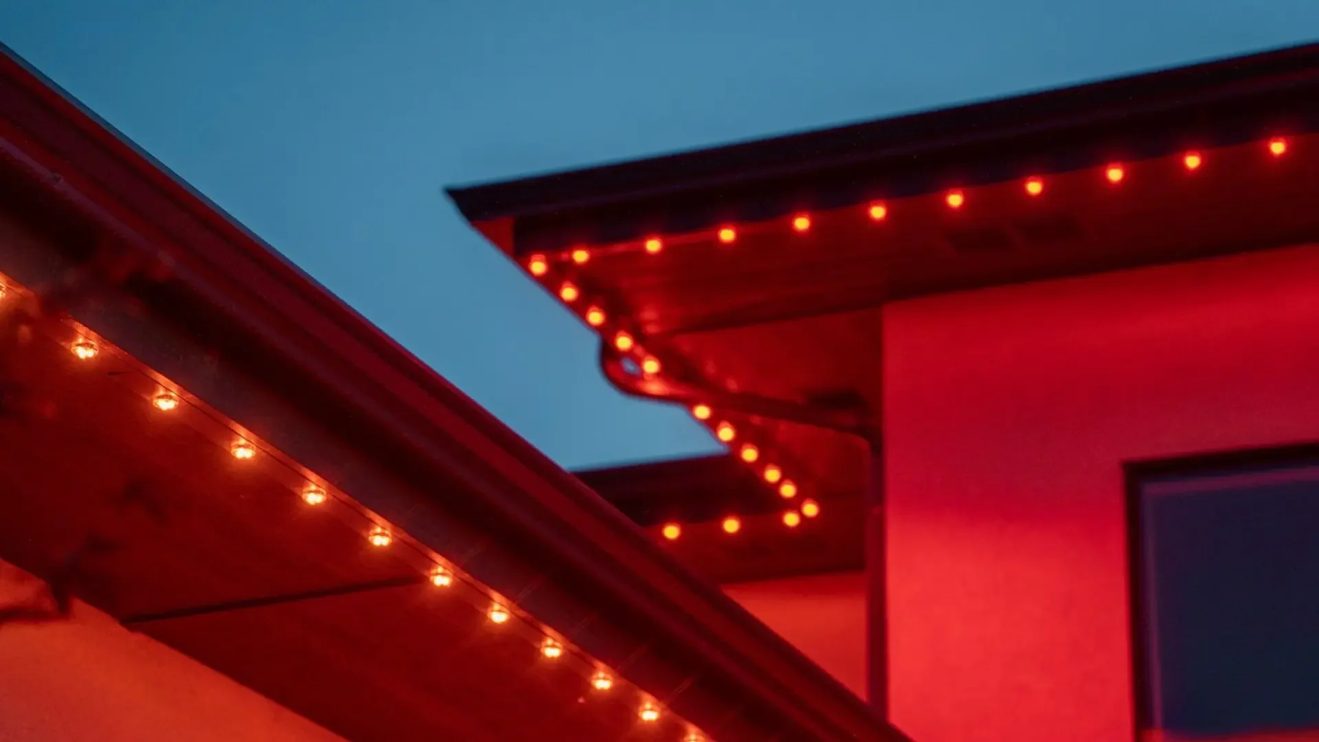 Night view of building with red neon lights outlining the roof and a section of the building's corner against a dark blue sky.