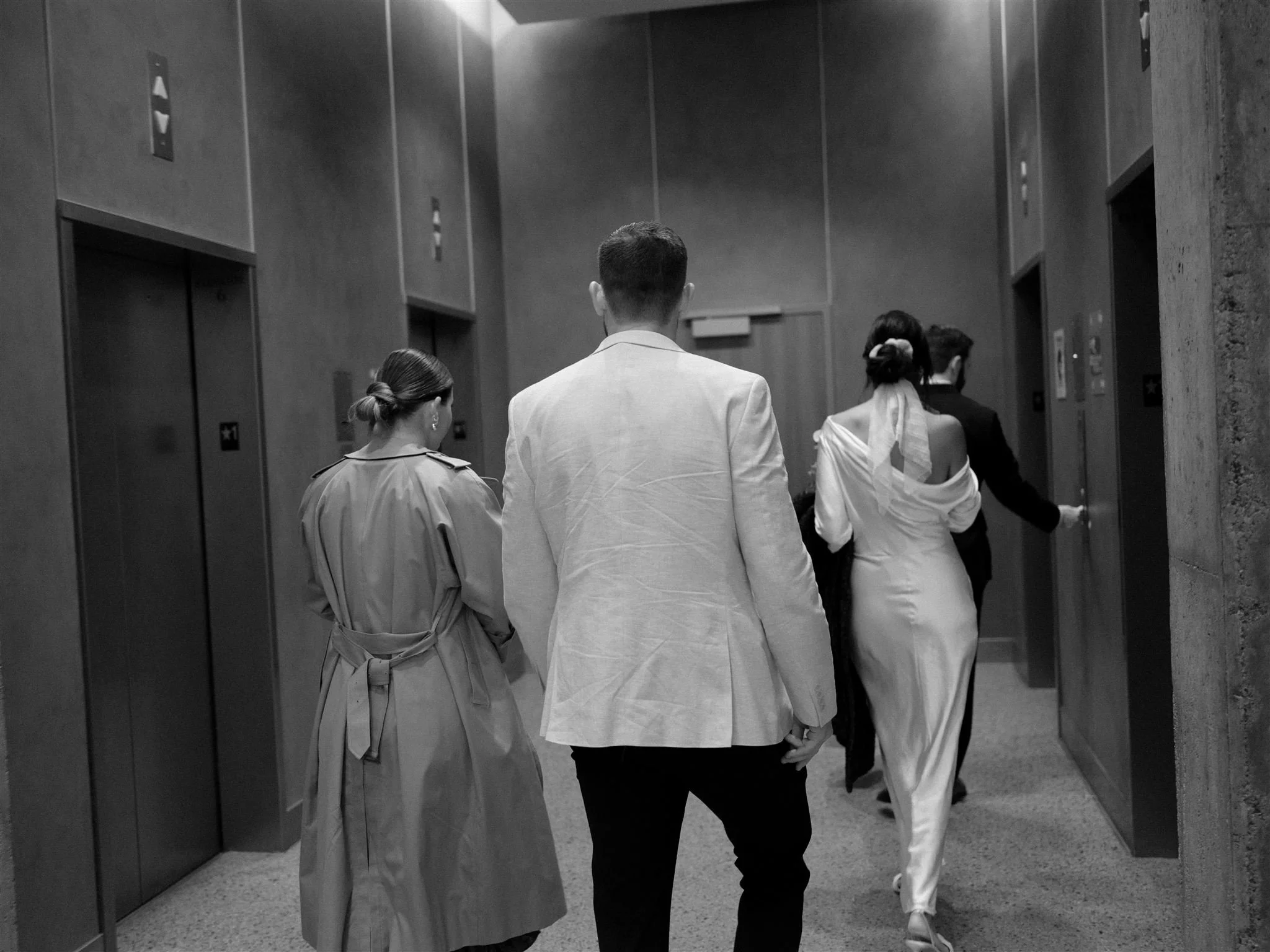 Wedding party walking down a quiet hallway inside the Seattle Municipal Courthouse, captured in black and white during an intimate courthouse wedding.