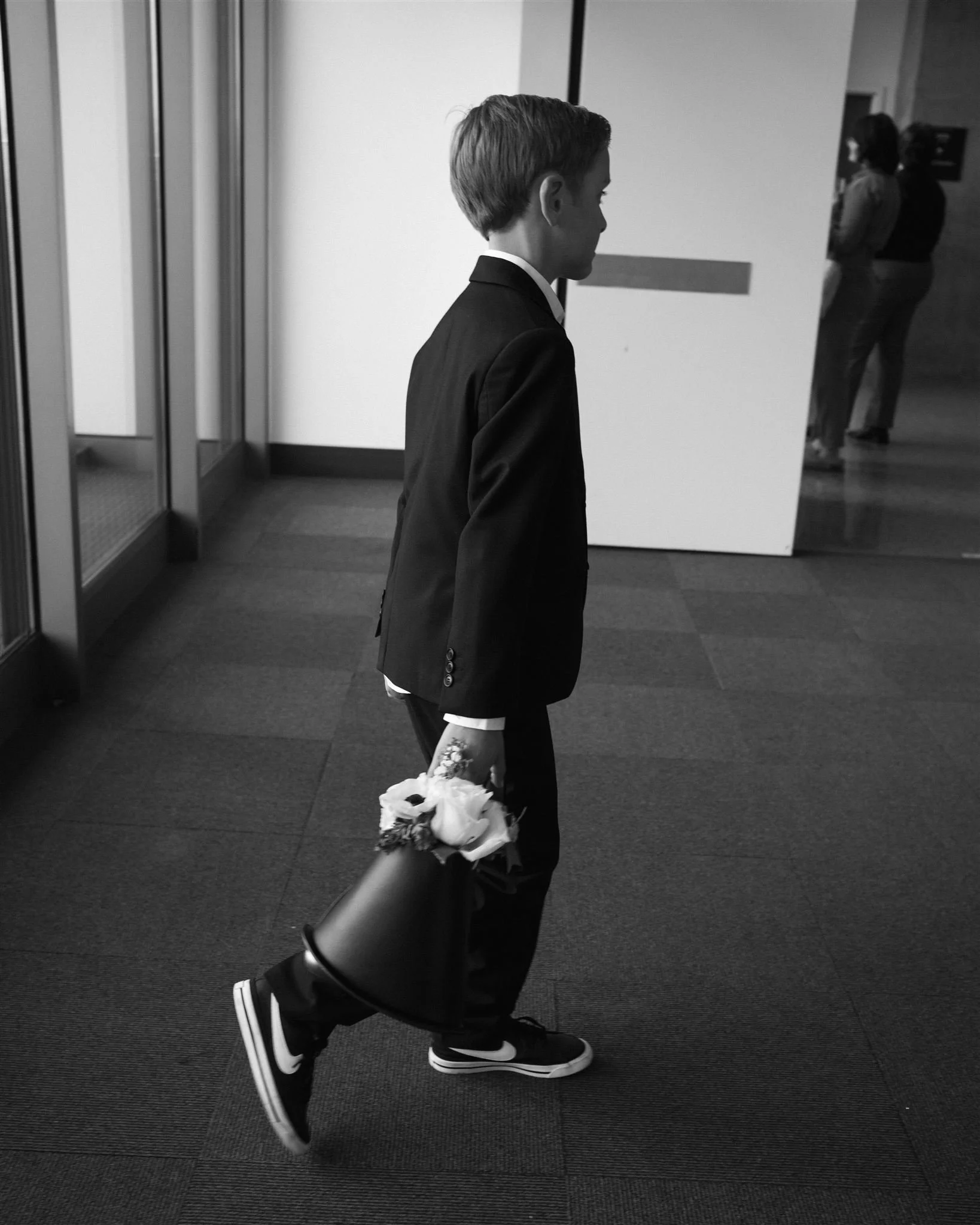 A young child dressed in a suit carrying a small bouquet inside the Seattle Municipal Courthouse during a modern courthouse wedding.