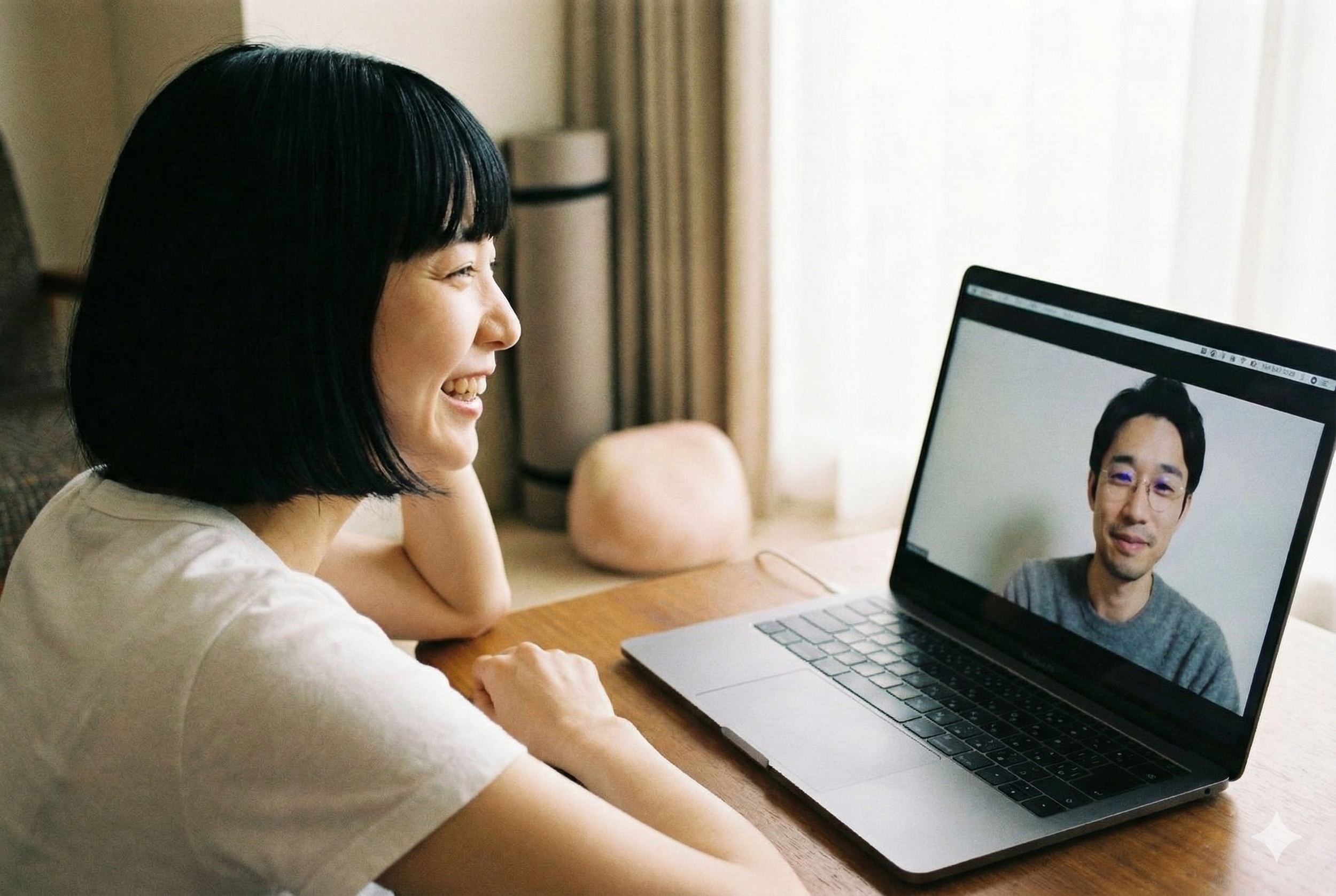 女性がノートパソコンの画面を見ながら笑顔で話す。