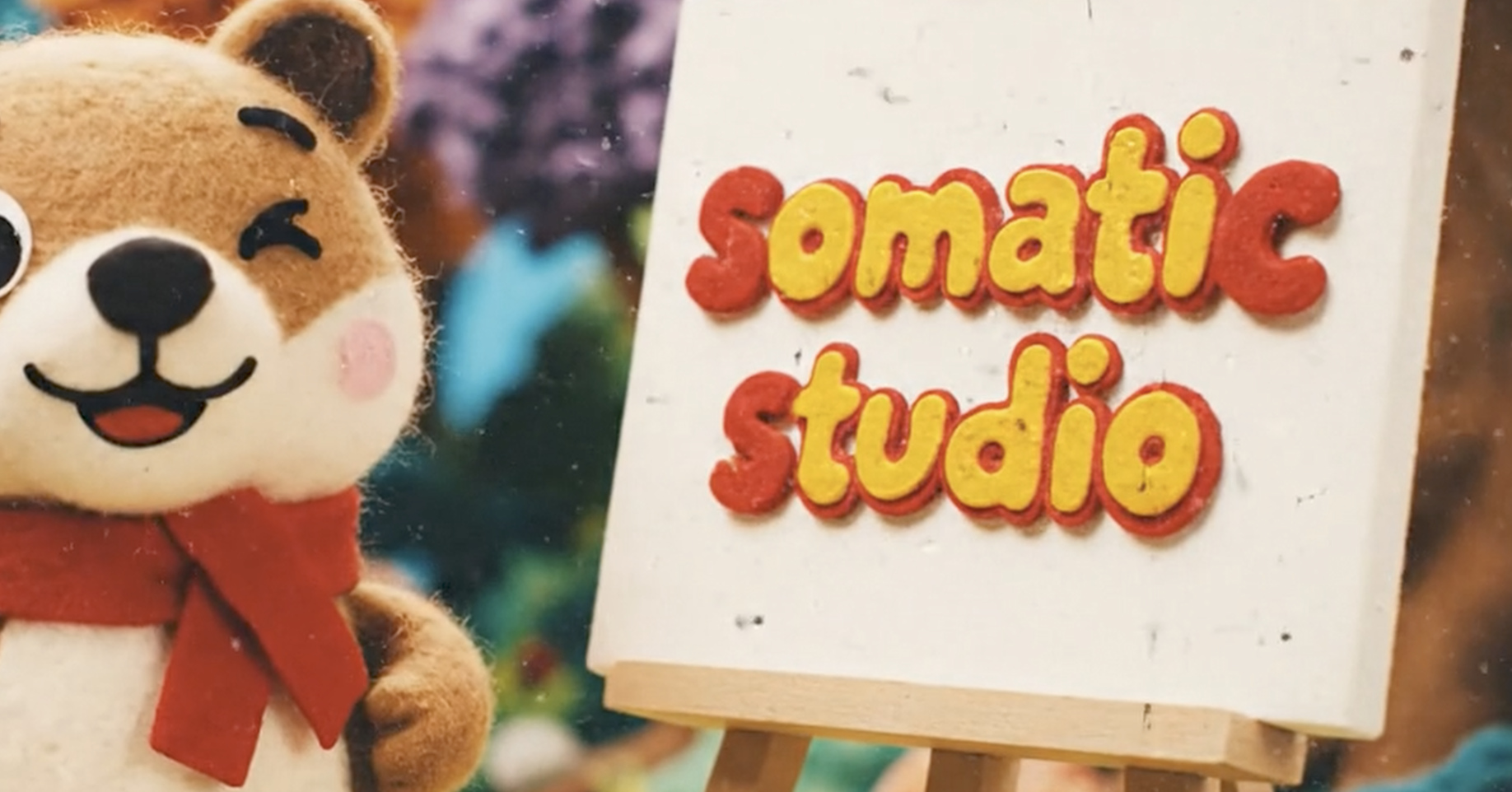 フェルトでできたクマのぬいぐるみとカラフルな文字で書かれた『Somati studio』のサインボードです。
