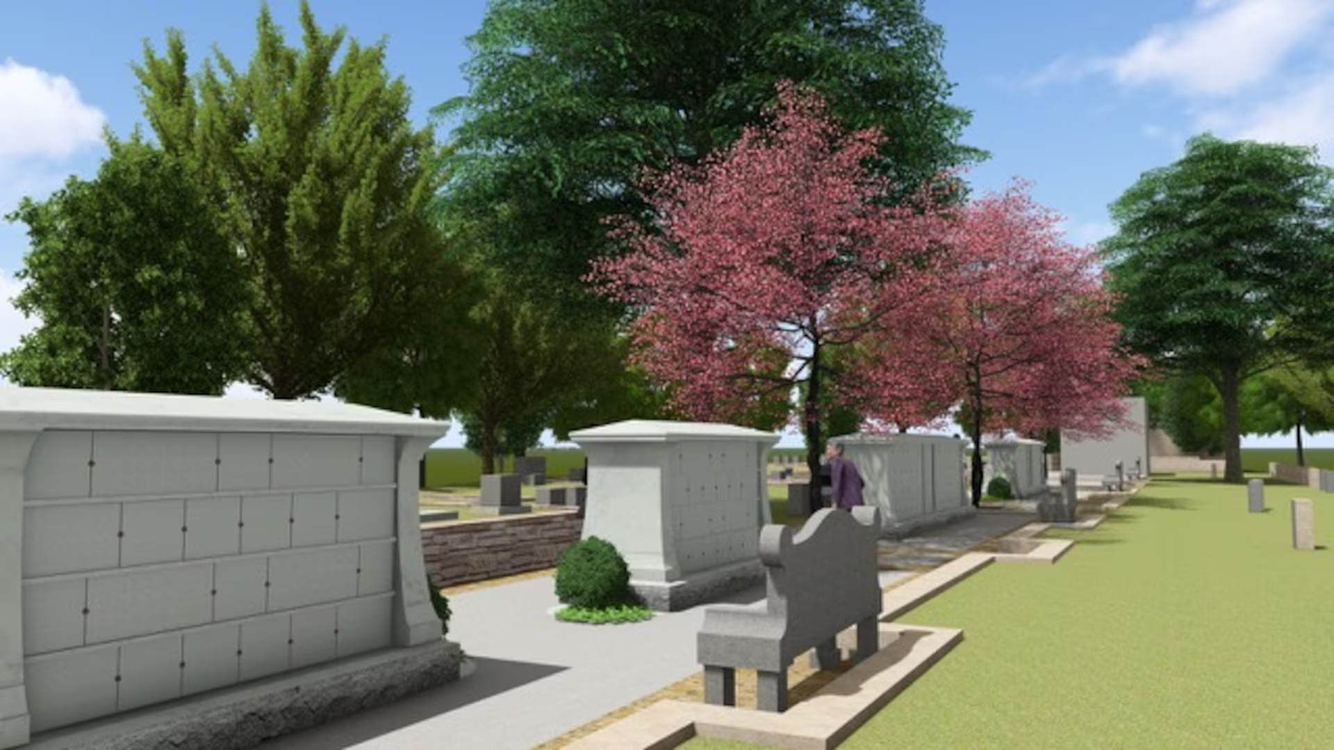 A cemetery with various tombstones and graves, surrounded by trees with green and pink foliage, and a white wall in the background under a blue sky.