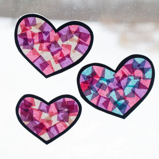 Three multicolored mosaic-style heart stickers on a window.