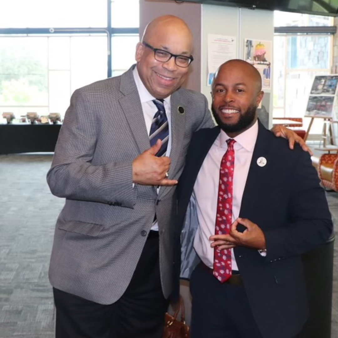 This is Dr. Dexter Shorter posing with his mentor. Both are dressed in business attire.