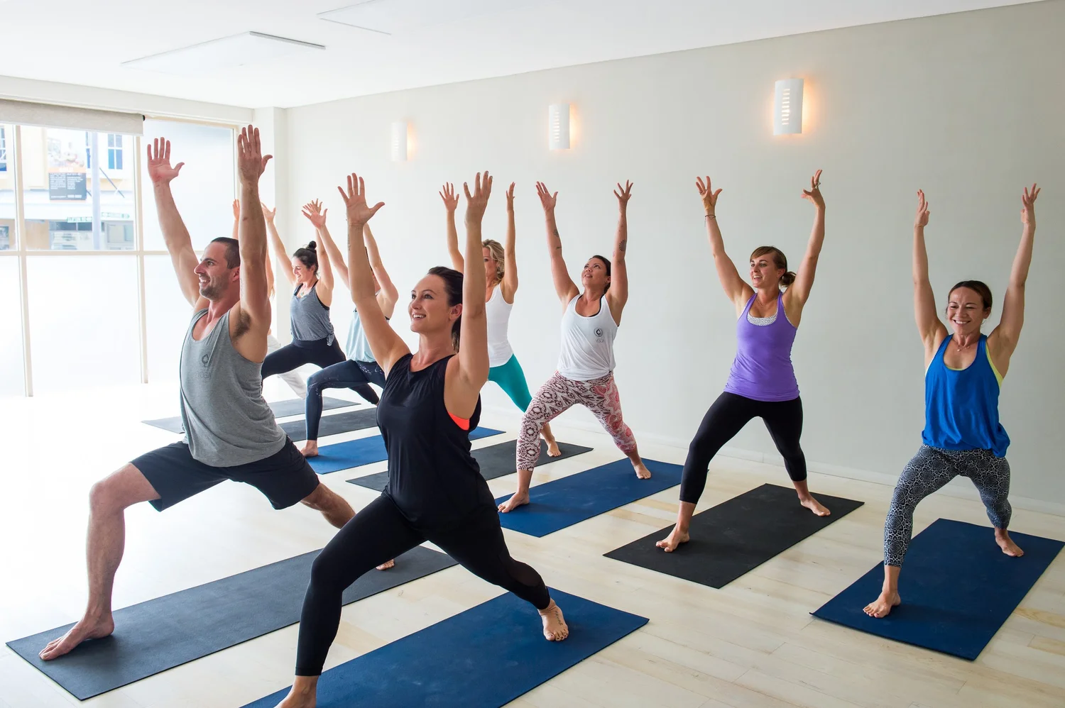 A yoga class holding warrior pose at This Is Yoga