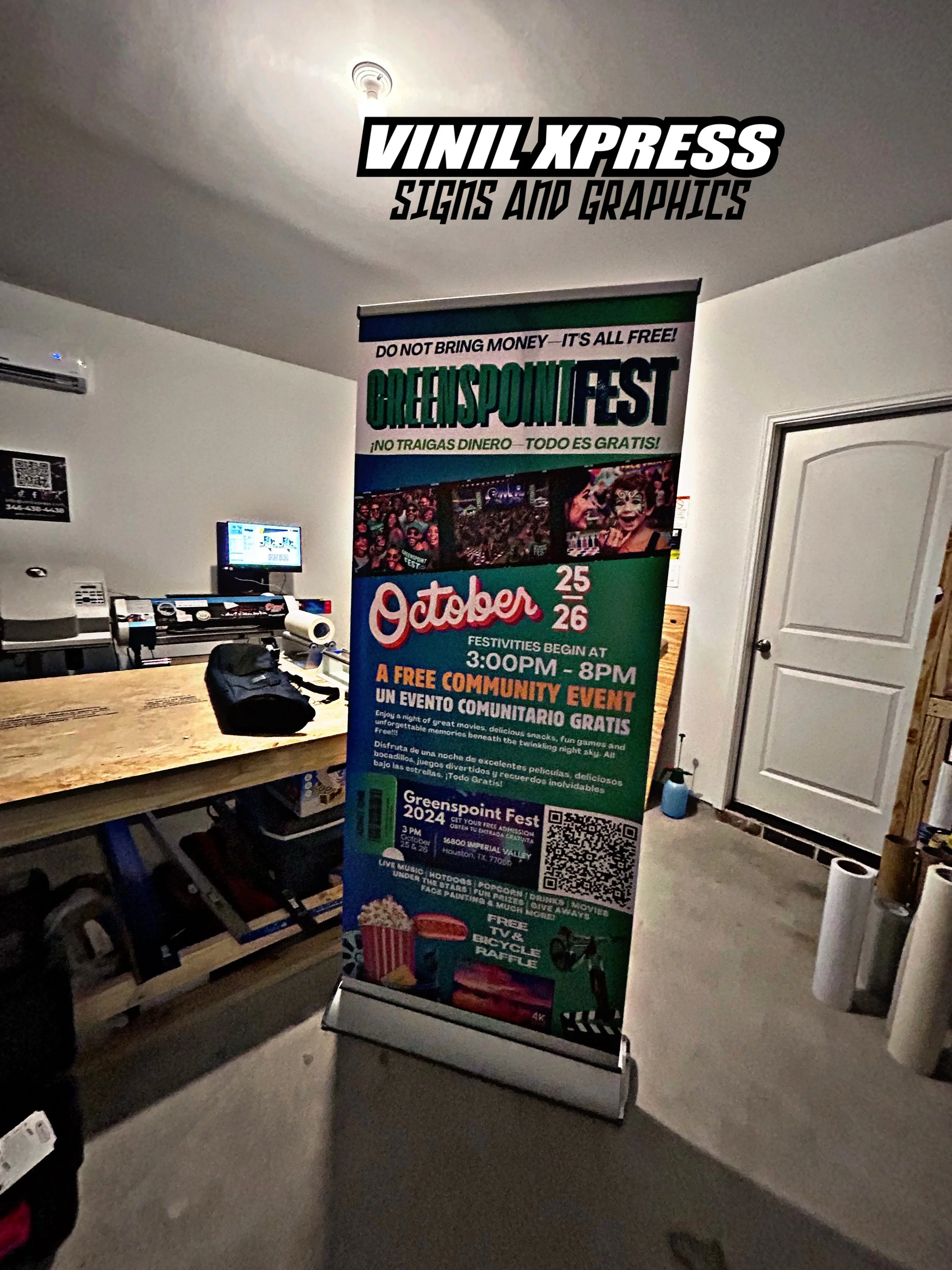 Vertical sign advertising Greenpoint Fest on October 25-26 from 3:00 PM to 8:00 PM with free community activities, movies, and food, located indoors near a staircase.