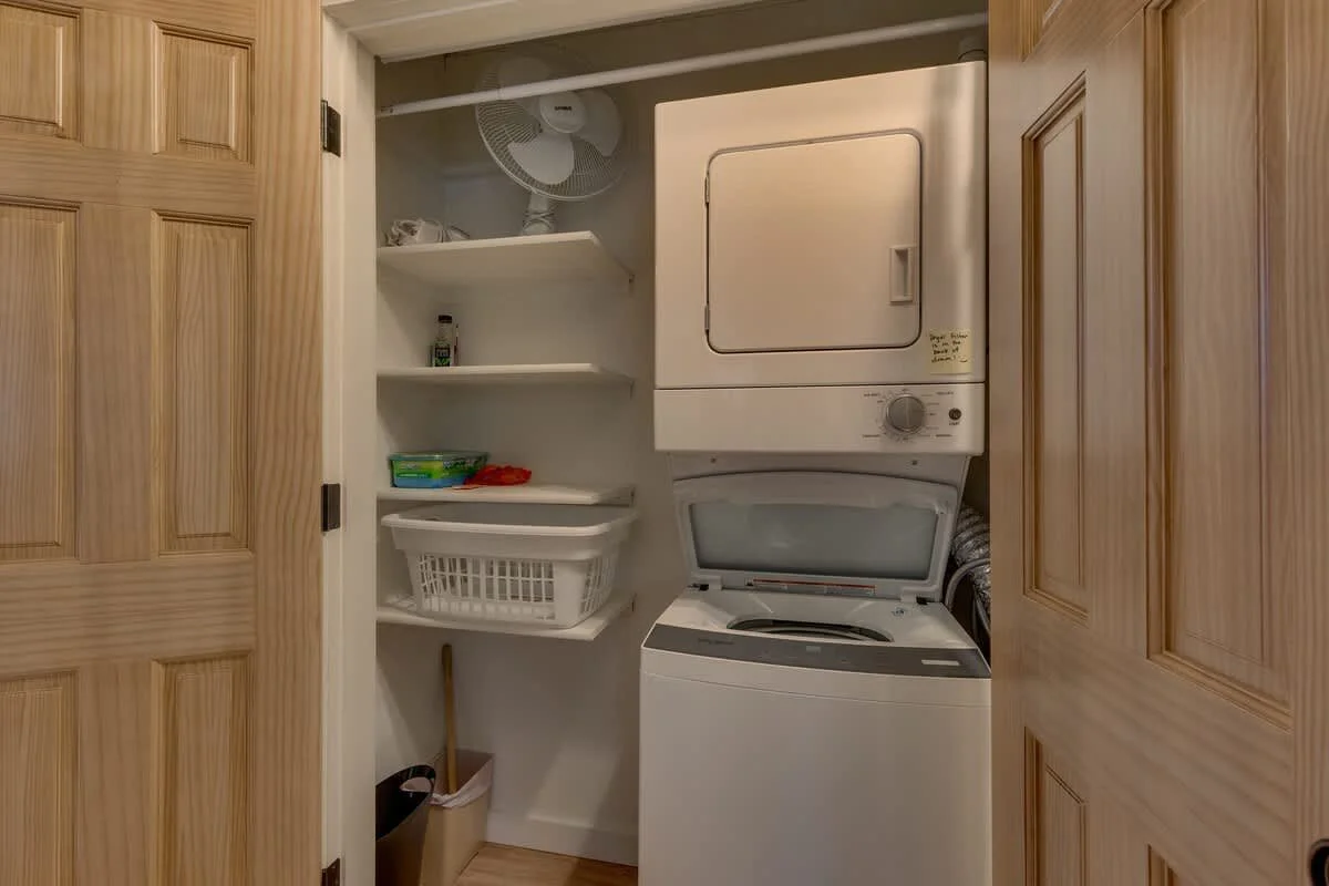laundry room with stacked washer dryer and shelves