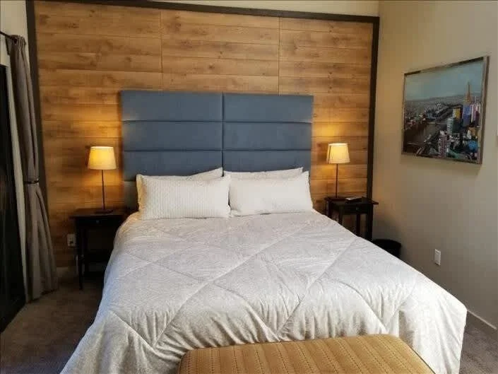 main bedroom with wooden wall and gray padded headboard