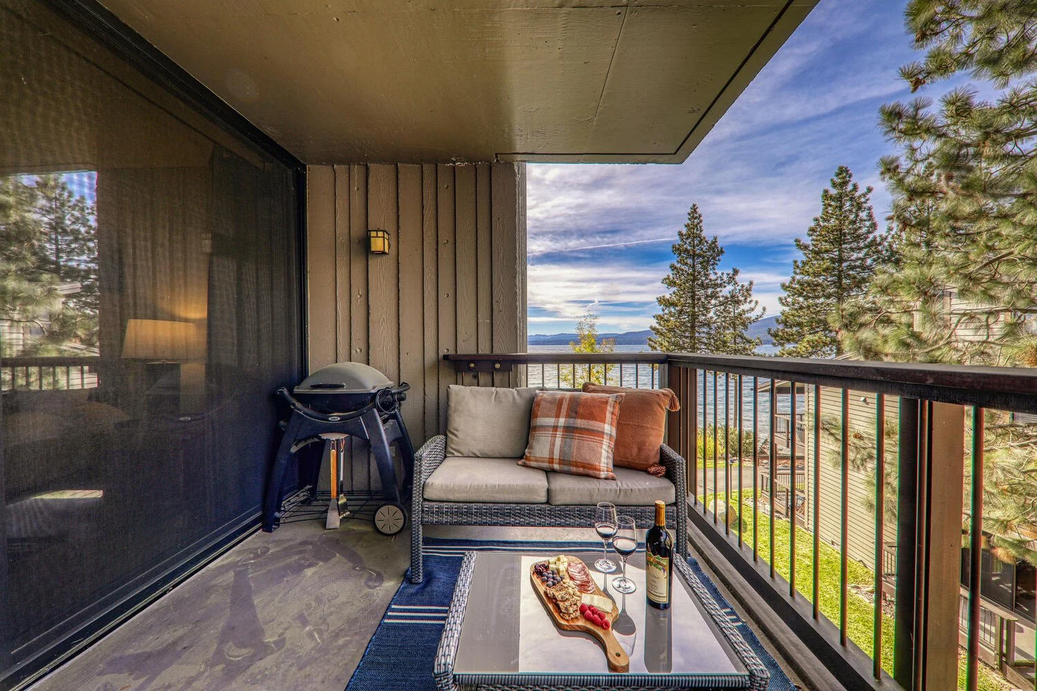 covered back deck with small view of lake, grill, chairs with cushions