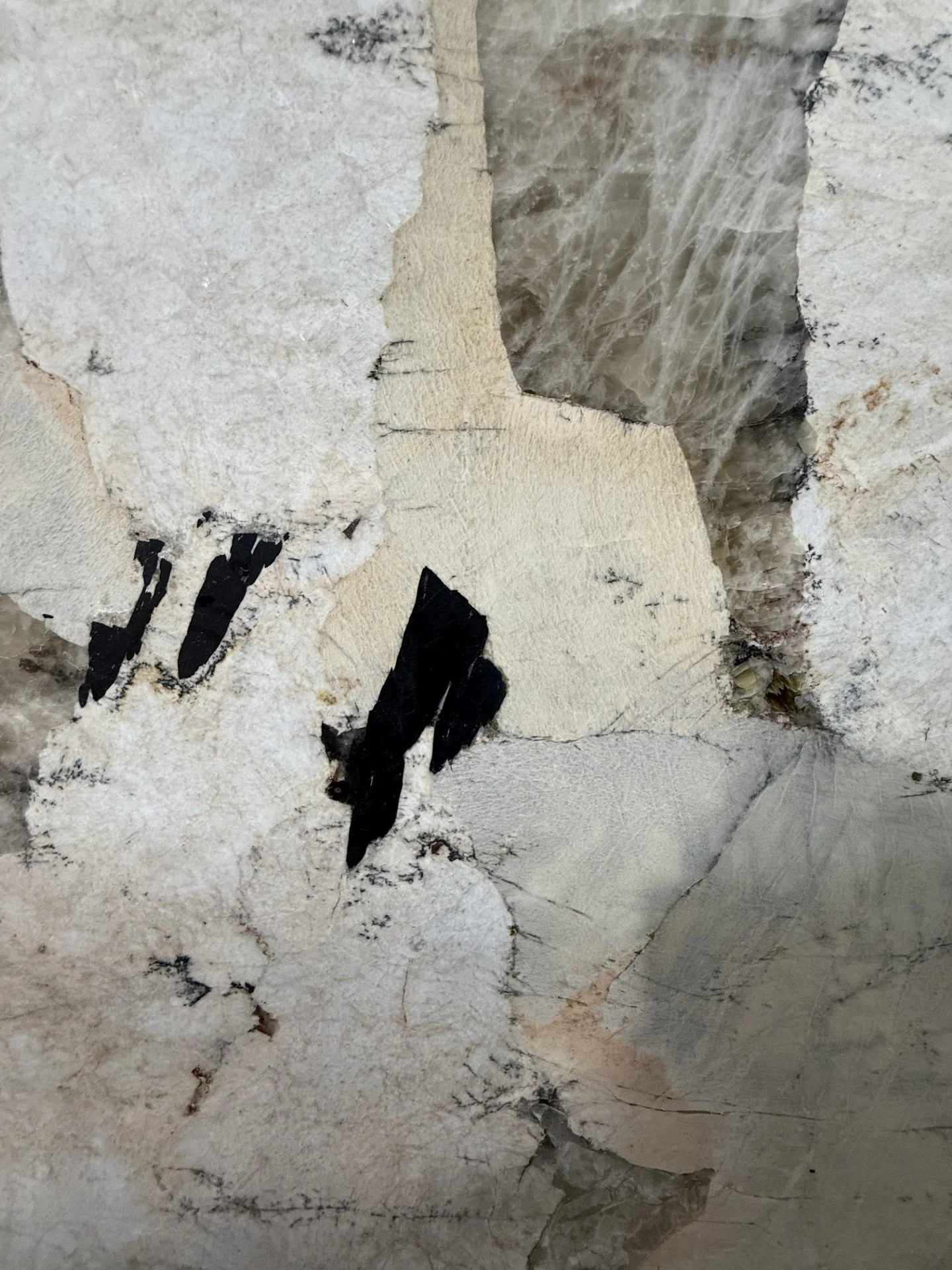 Close-up of torn, layered wallpaper with peeling edges, revealing underlying surfaces, including fabric and textured materials.