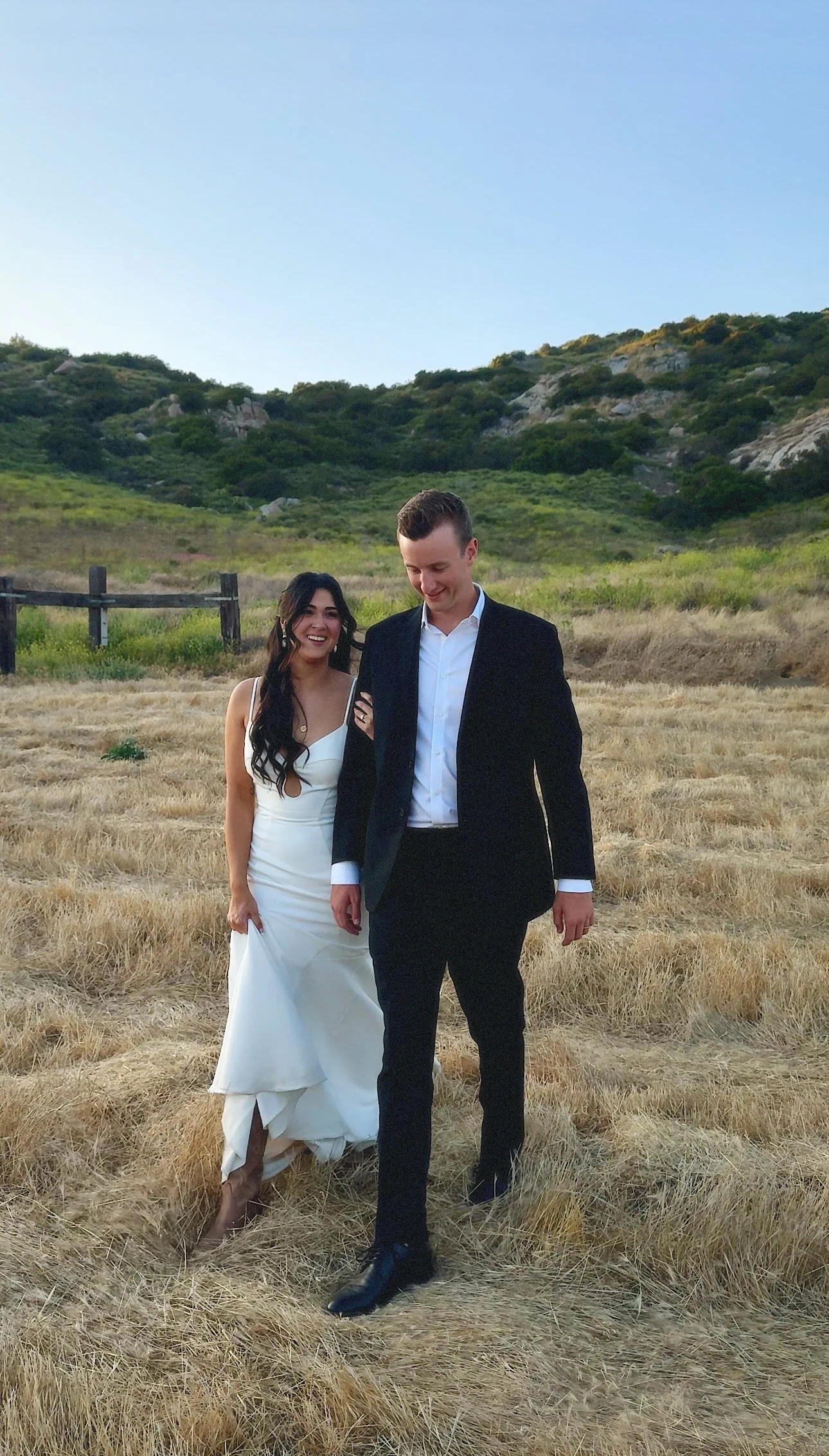 Bride and groom walking through a field at westwynd ranch in ramona california captured by san diego wedding content creator who captures behind-the-scenes wedding videos.