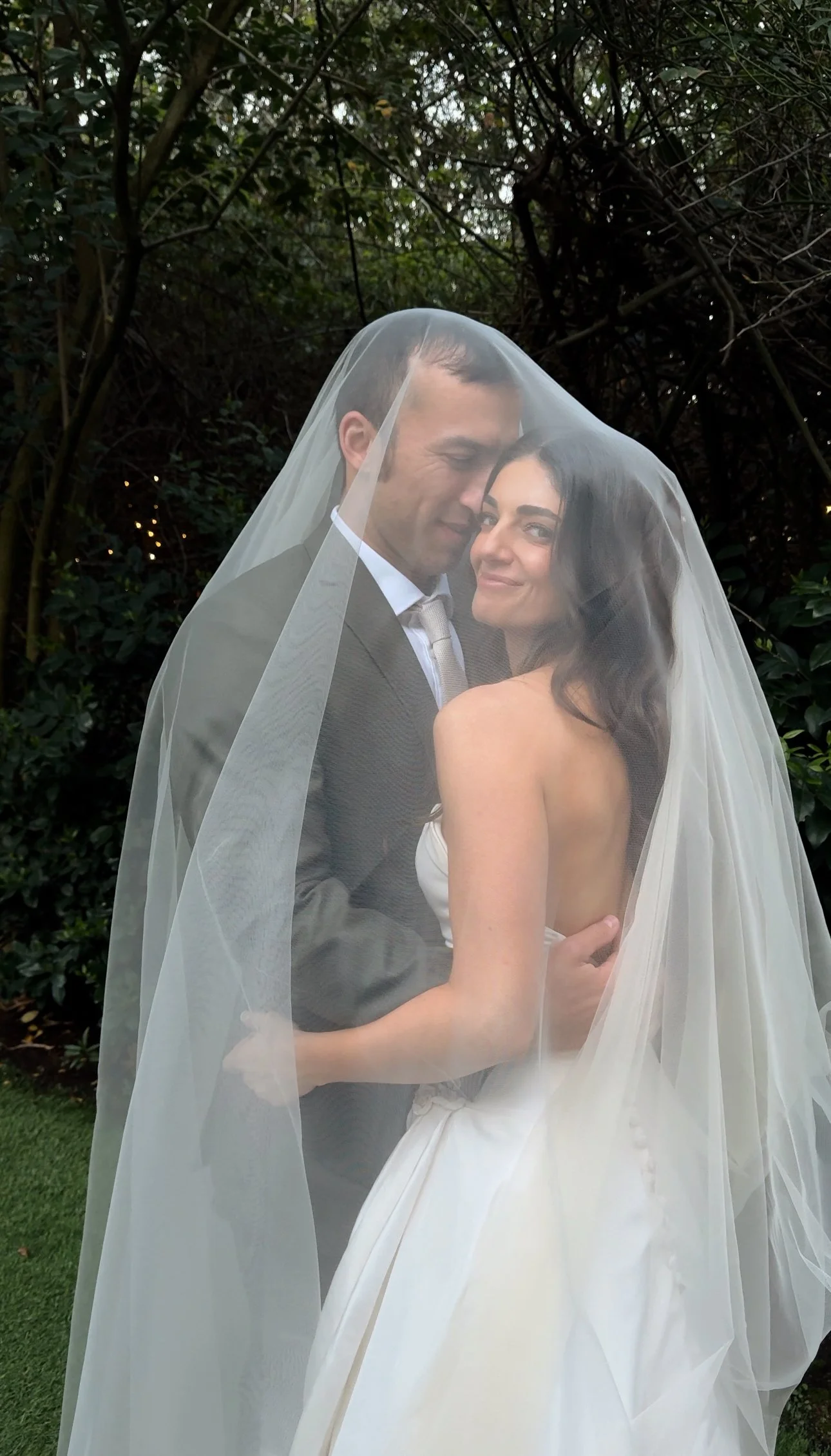 Bride and groom under the veil at Twin Oaks Gardens in San Marcos captured by san diego wedding content creator who captures behind-the-scenes wedding videos.